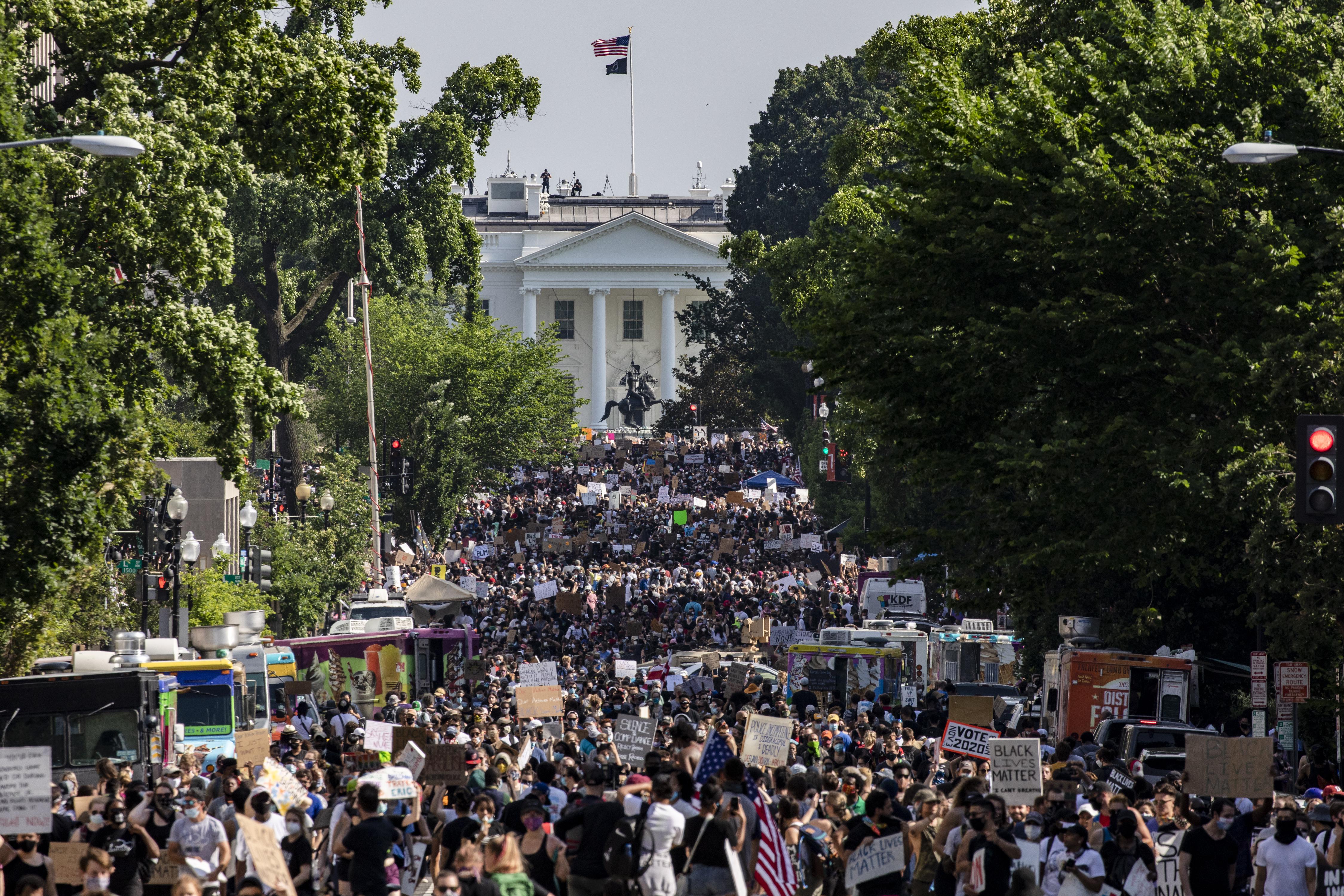 Protesters march in the street, with the White House in the background