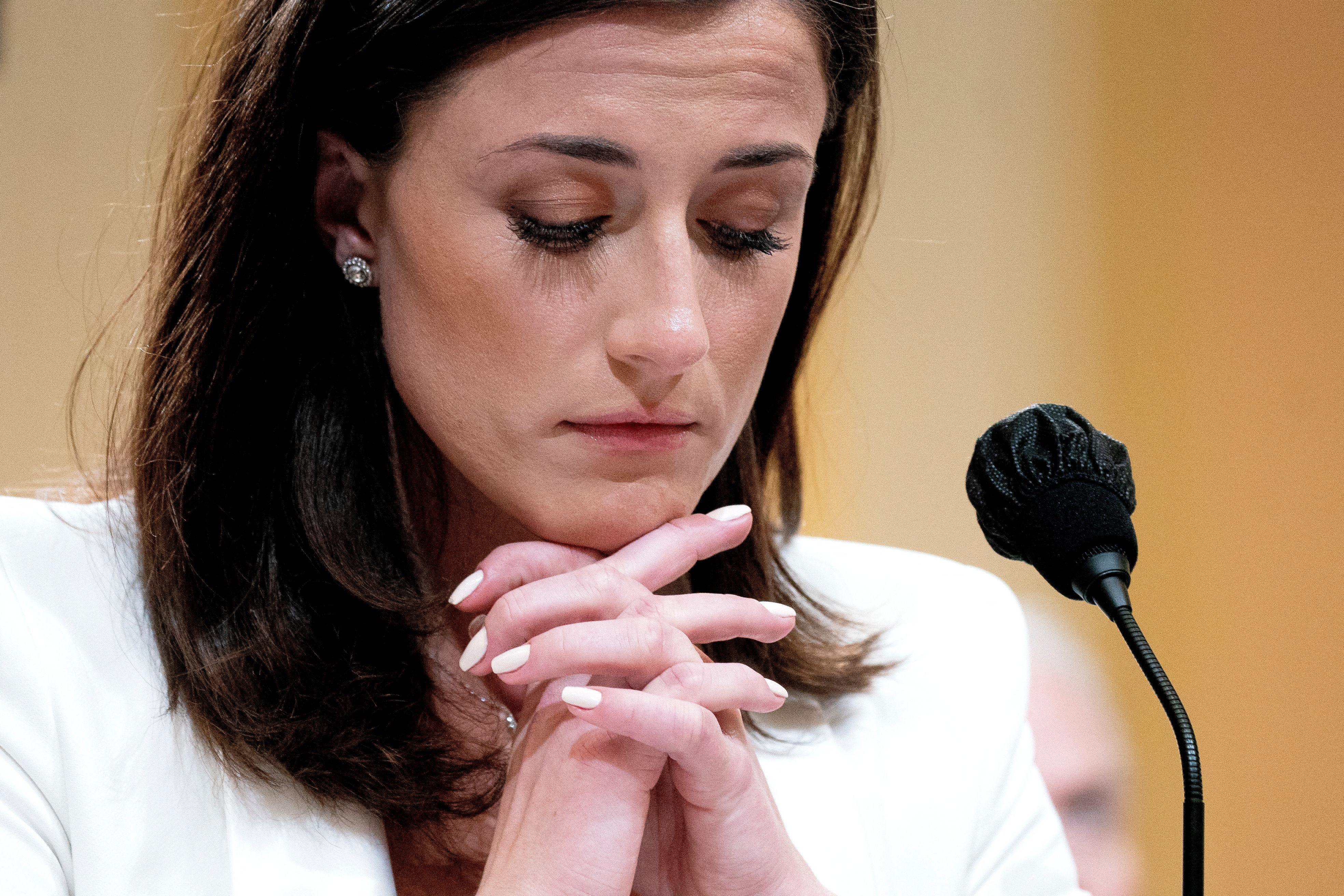 Cassidy Hutchinson, a top aide to former White House Chief of Staff Mark Meadows, listens during the sixth hearing by the House Select Committee to Investigate the January 6th Attack on the US Capitol, in the Cannon House Office Building in Washington, DC, on June 28, 2022. Her hands are clasped under her chin.