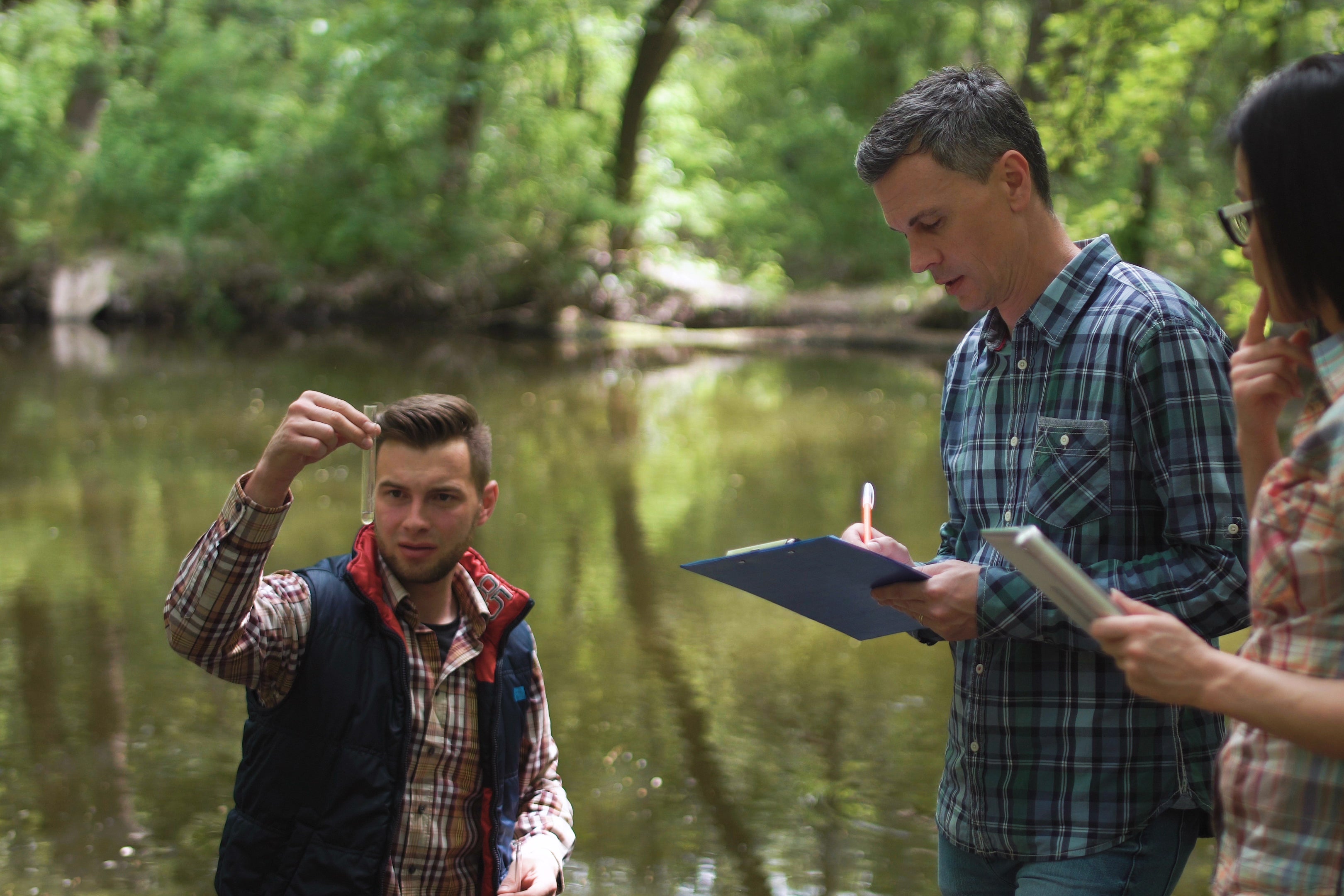 Three scientists analyze a water sample from a lake.