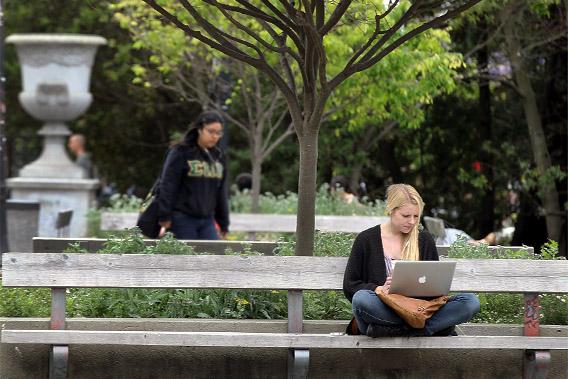 A UC Berkeley student works on her laptop while sitting on the UC Berkeley campus.