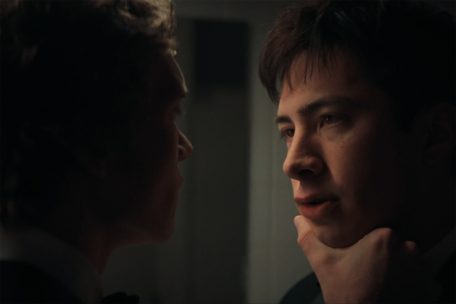 A man holds another man by his chin.