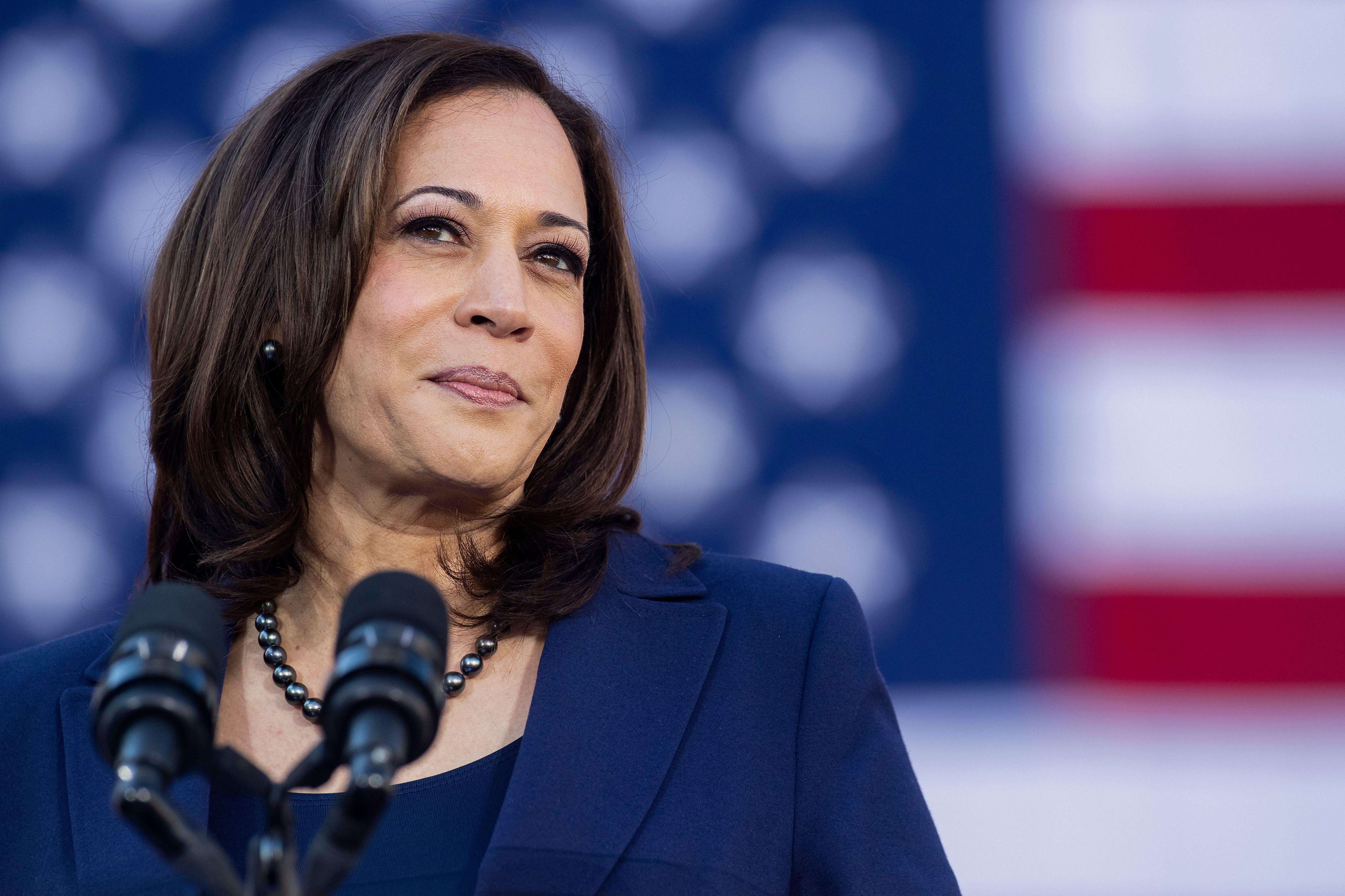 Kamala Harris standing at a mic in front of an American flag