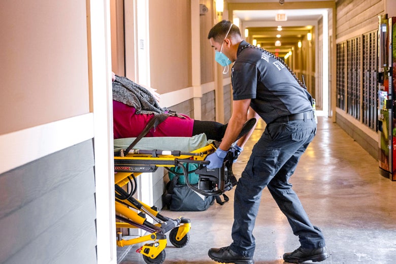A paramedic wheels a woman into a hospital room.