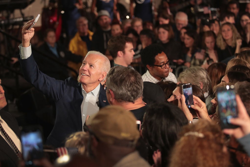 Biden takes a selfie with a fan in a crowd of supporters.