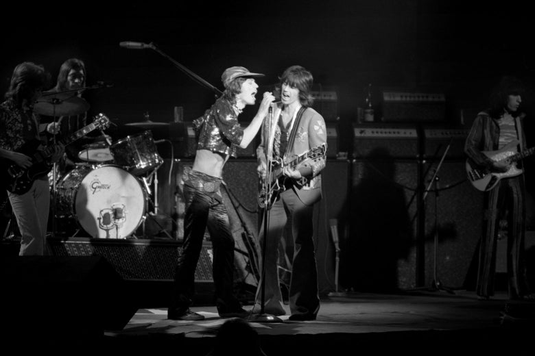 The Rolling Stones perform on stage in a black-and-white photo.