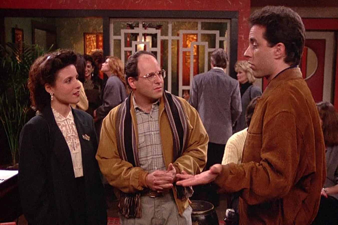 Elaine, George, and Jerry talk inside a restaurant.