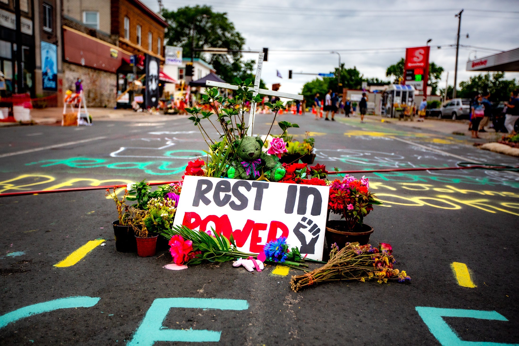 A sign and flowers in the middle of the street.