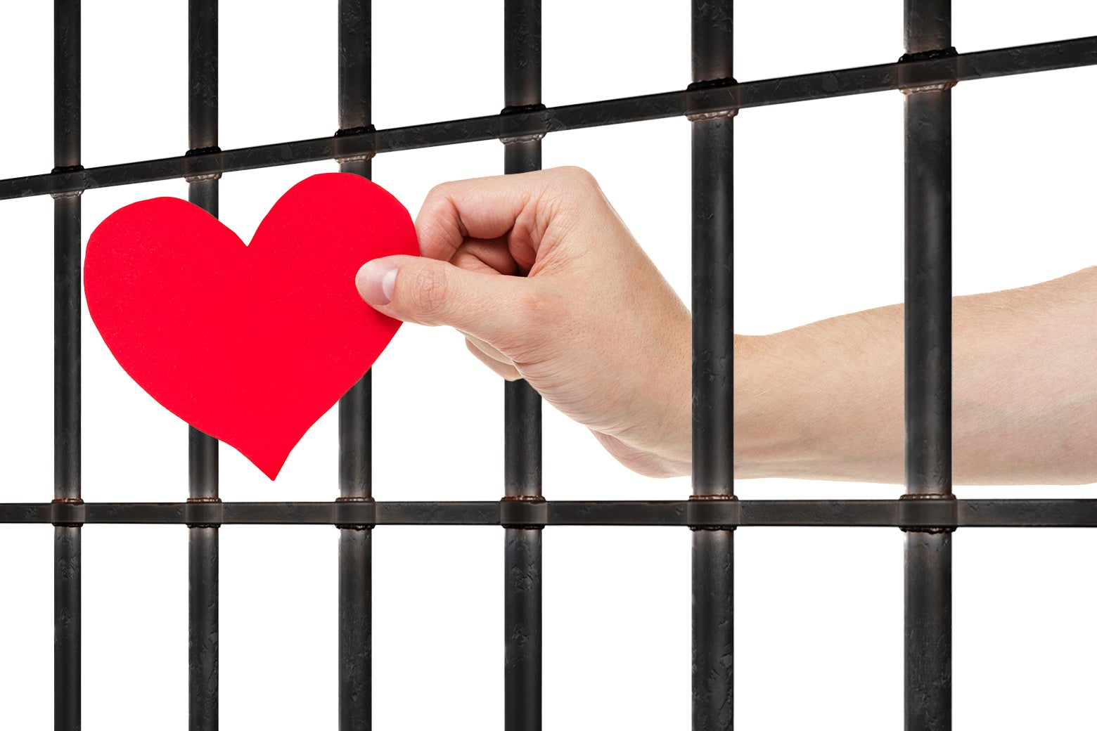 A hand holds a bright red heart out through prison bars. 