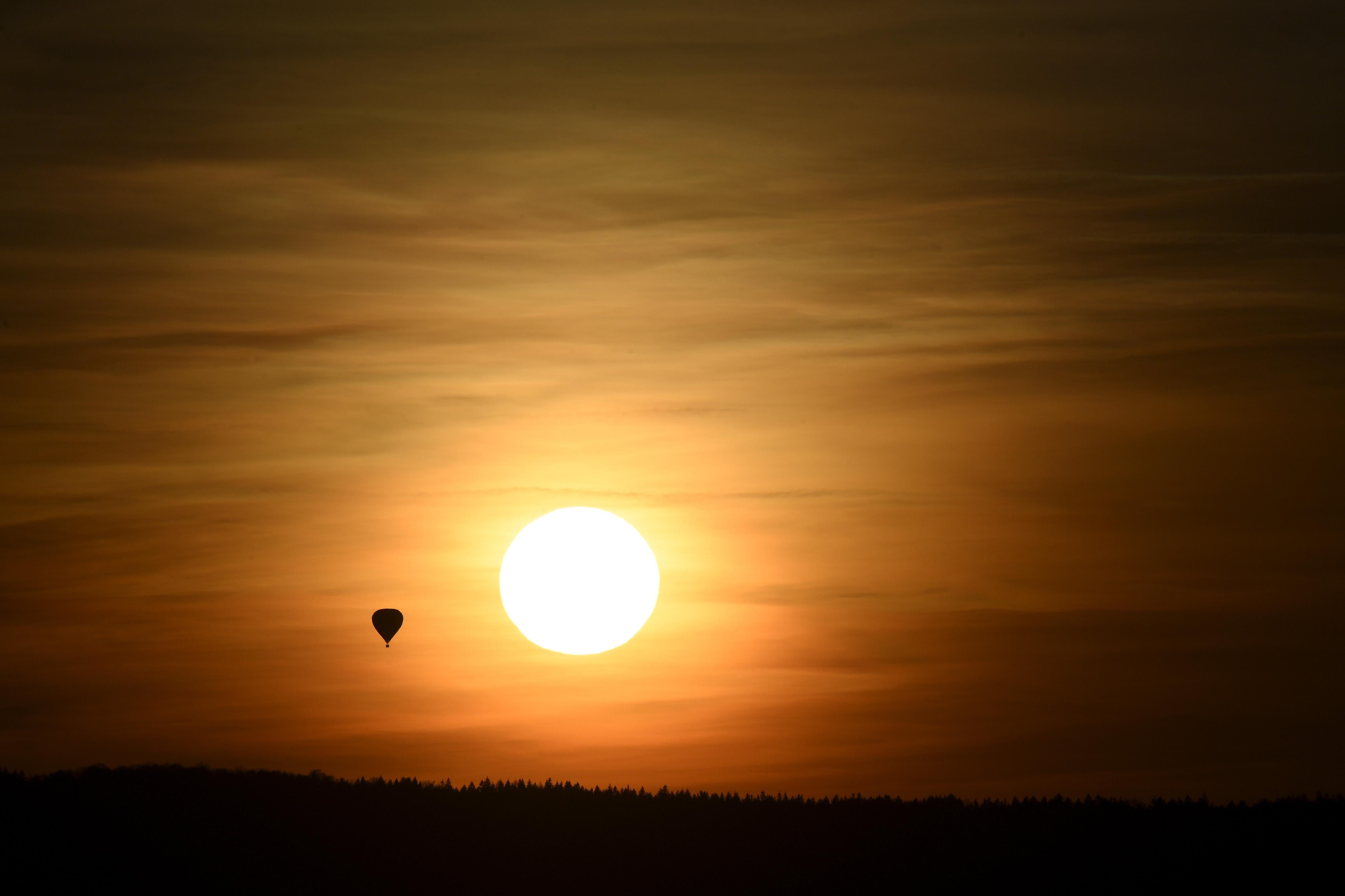 A hot air balloon flies as the sun sets.