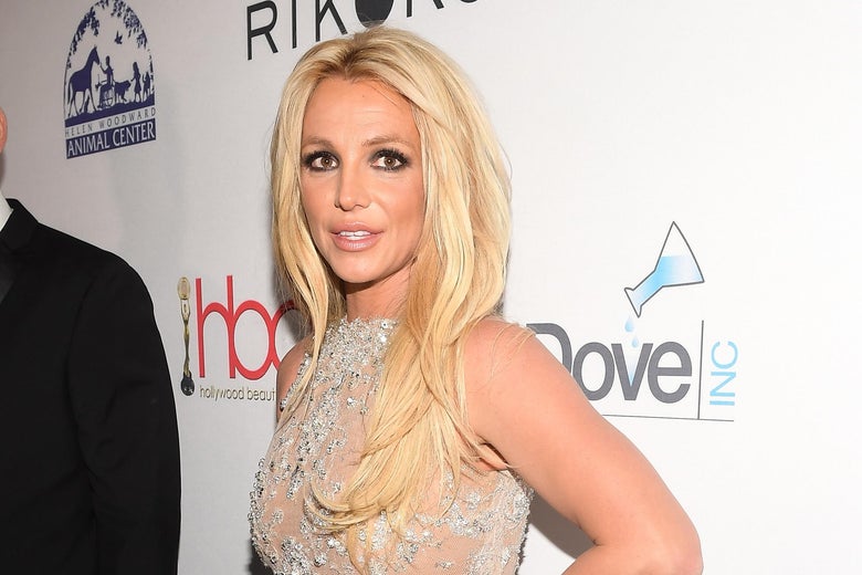 Britney Spears with her hand on her hip on a red carpet.