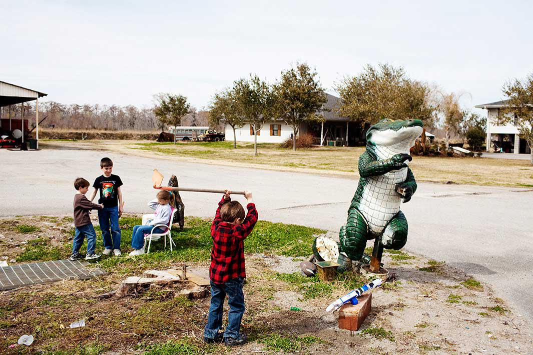Spencer Bonnecarrere, 6, chops at the dirt in front of the office of Daneco Alligator Farm in Houma, Louisiana on Thursday, February 18, 2010 as his siblings Stephen Paul, 10, Stuart, 5, and cousin Victoria Bourg, 6, play in the background.