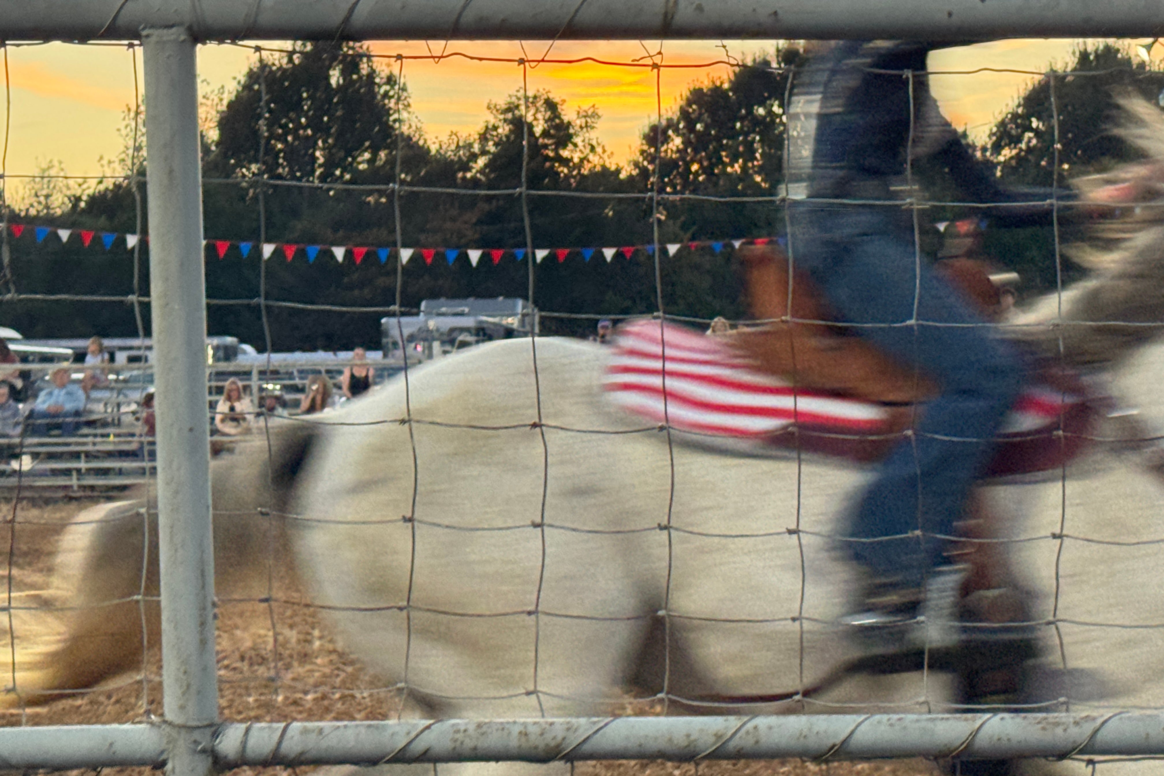 A horse with an American flag saddle in motion at the rodeo.