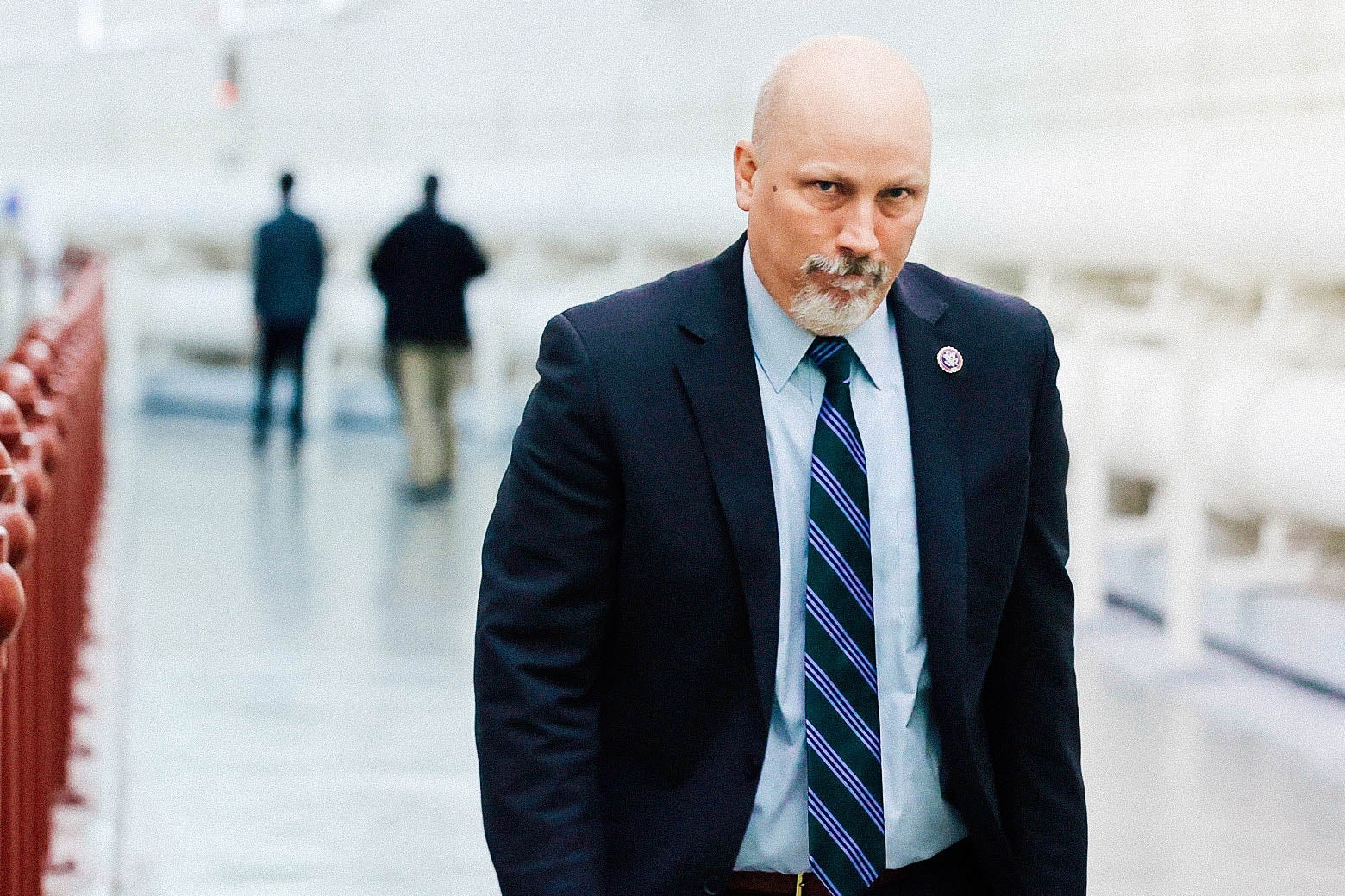 Roy walking in a hallway, looking sternly at the camera