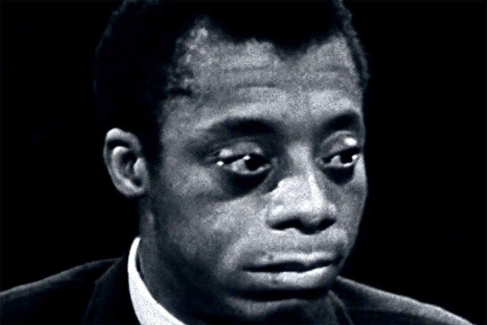 Close up of James Baldwin at a microphone.