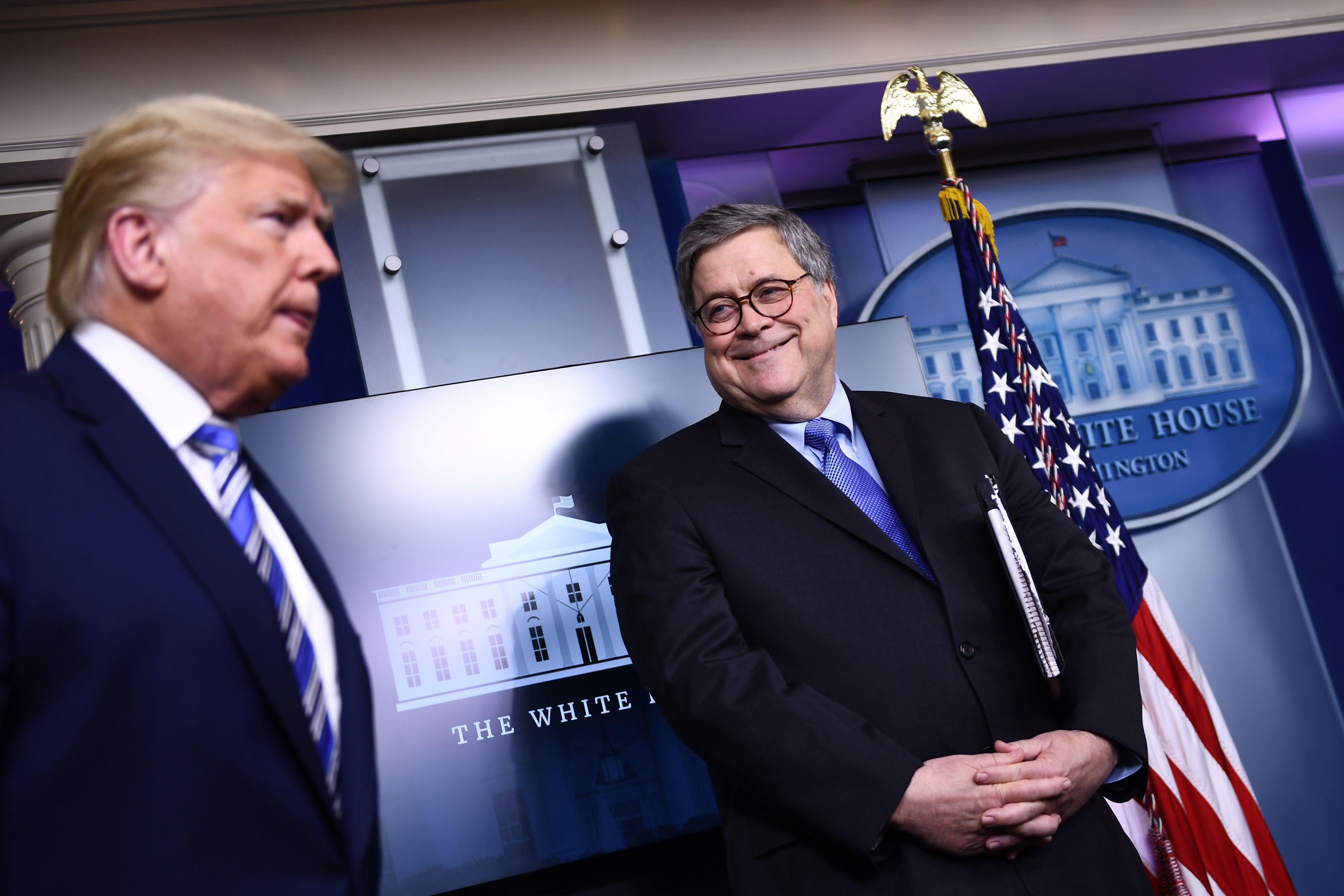 Barr smiles at Trump in the White House press room.