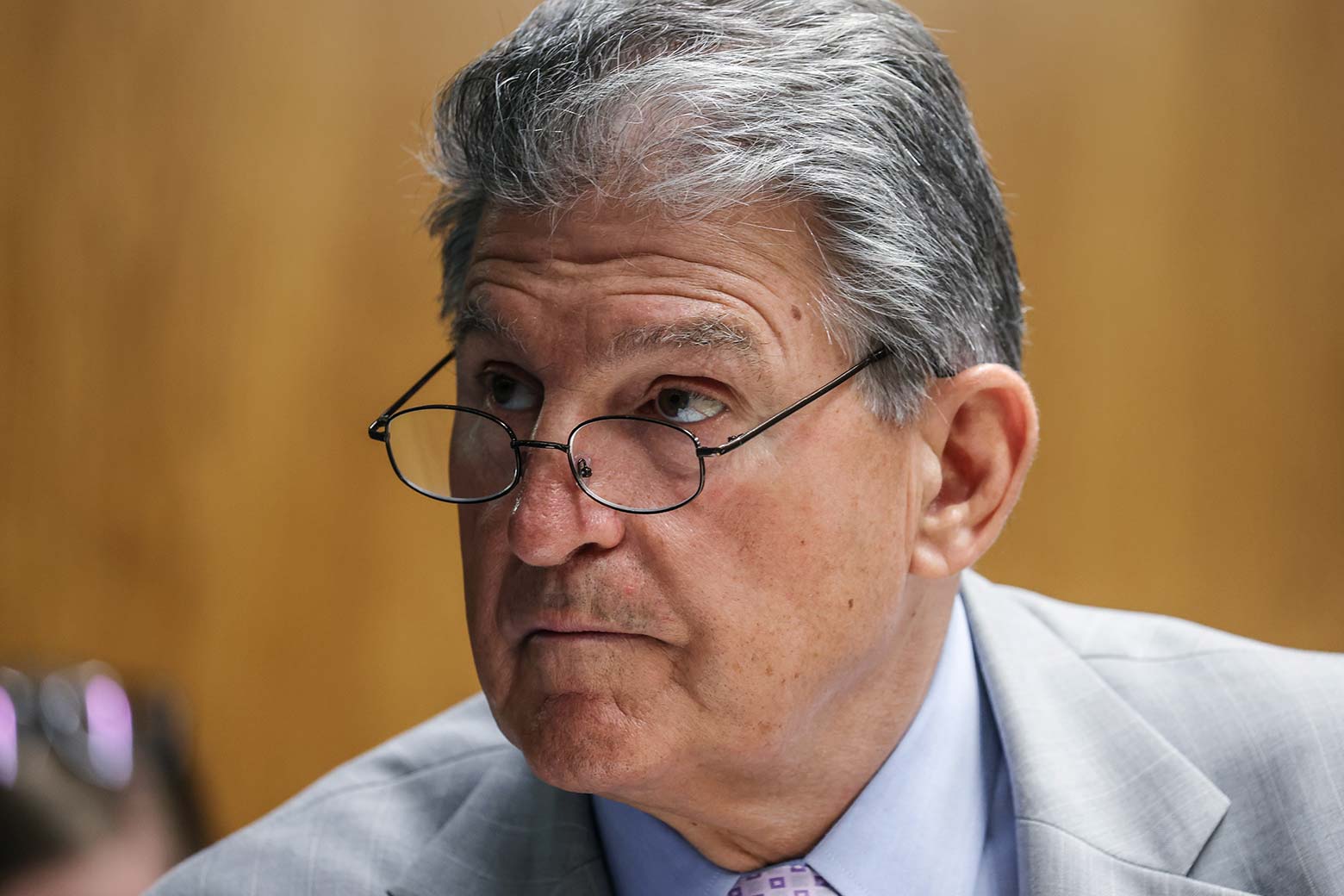 Joe Manchin looks upward over his glasses while at a hearing on Capitol Hill.