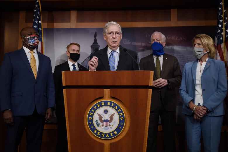 Mitch McConnell speaking at a podium with Tim Scott standing by