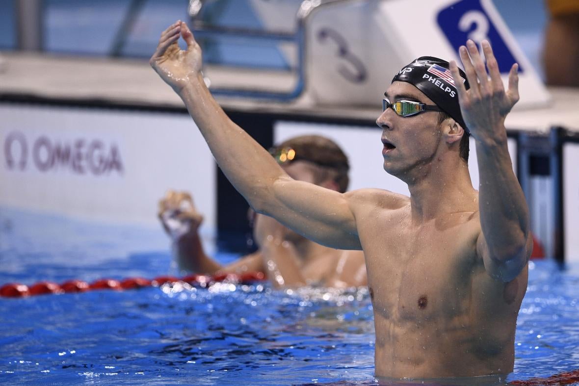 Phelps in goggles and swim cap, with his arms raised