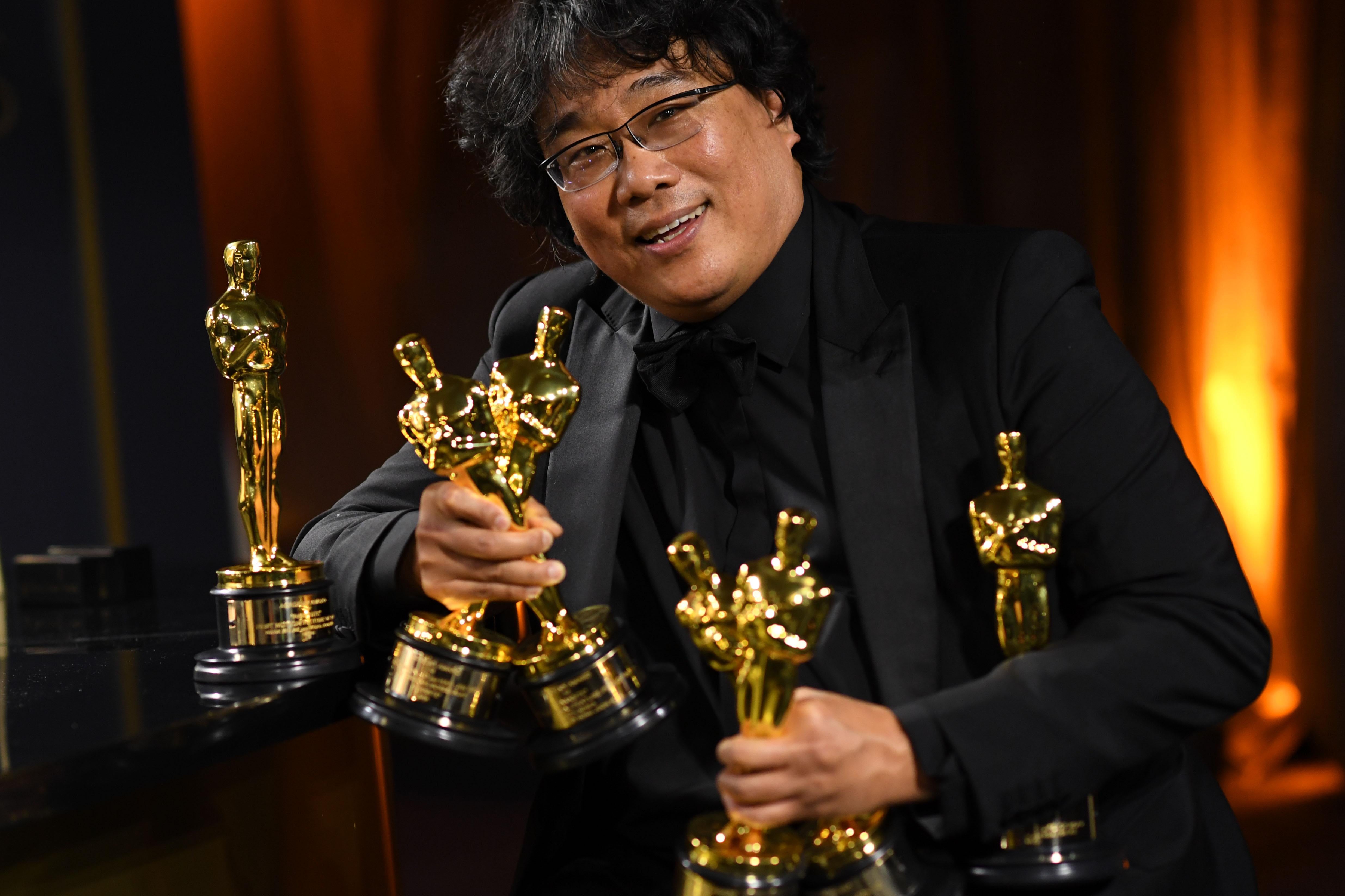 Bong Joon-ho poses with an armful of Oscars.