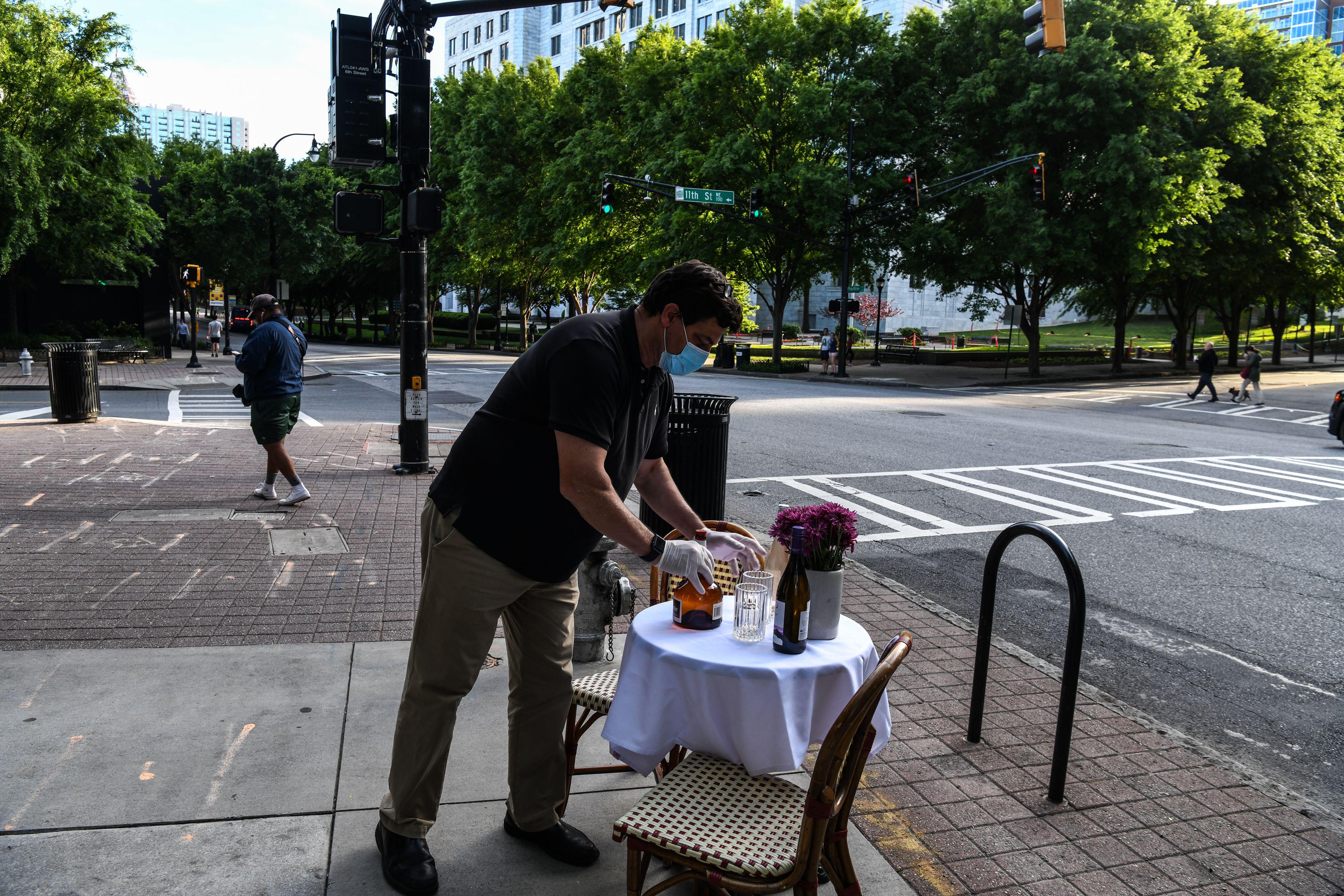 A man decorates a bistro table outside his restaurant amid the novel coronavirus pandemic in Atlanta, Georgia on April 27, 2020. - Some Georgia restaurants reopened on April 27, 2020 for limited dine-in service as the state loosened more coronavirus restrictions. (Photo by CHANDAN KHANNA / AFP) (Photo by CHANDAN KHANNA/AFP via Getty Images)