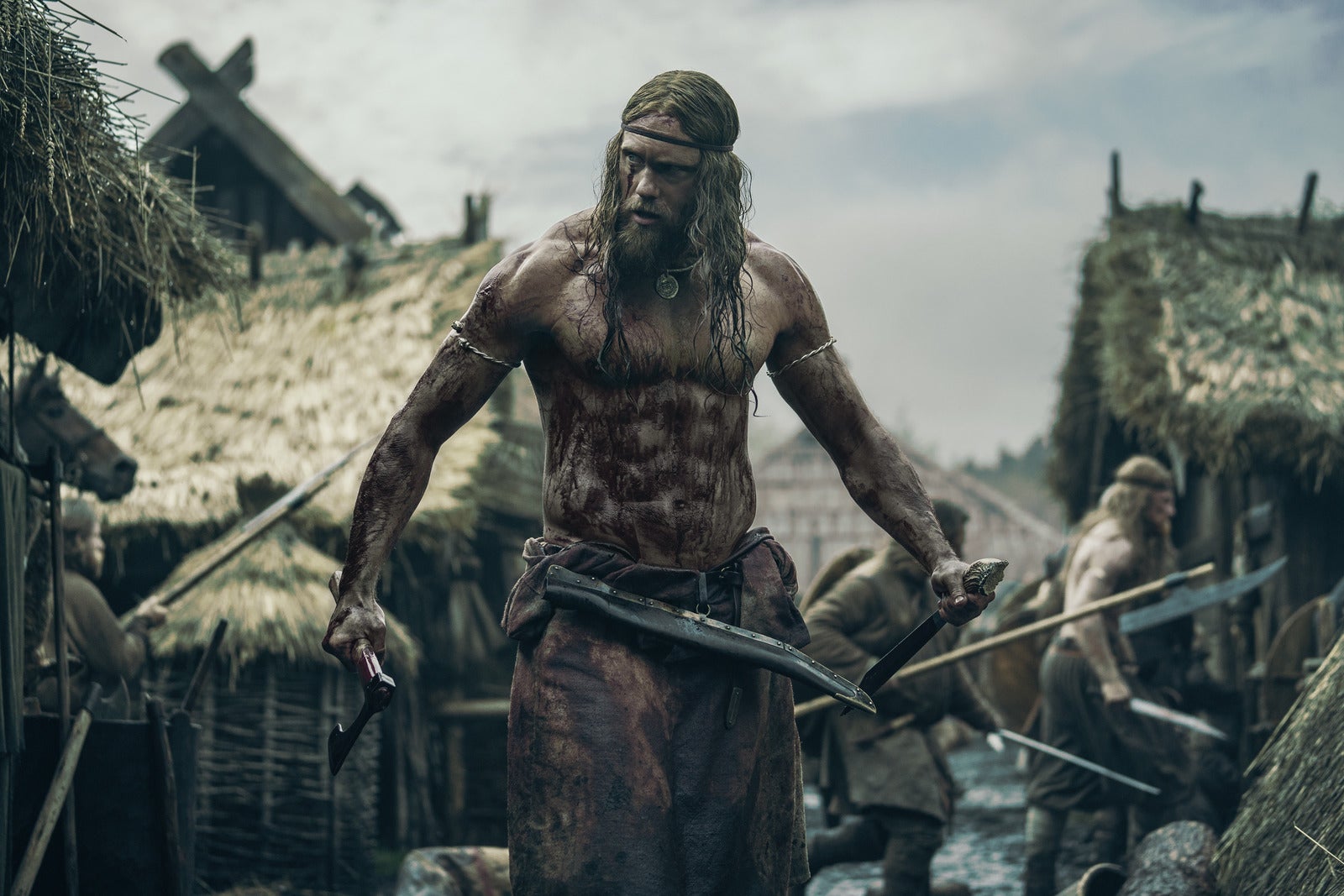 Alexander Skarsgard stands, shirtless and impossibly, steroidally ripped, an axe in each hand, blood on his chest, amid a medieval village