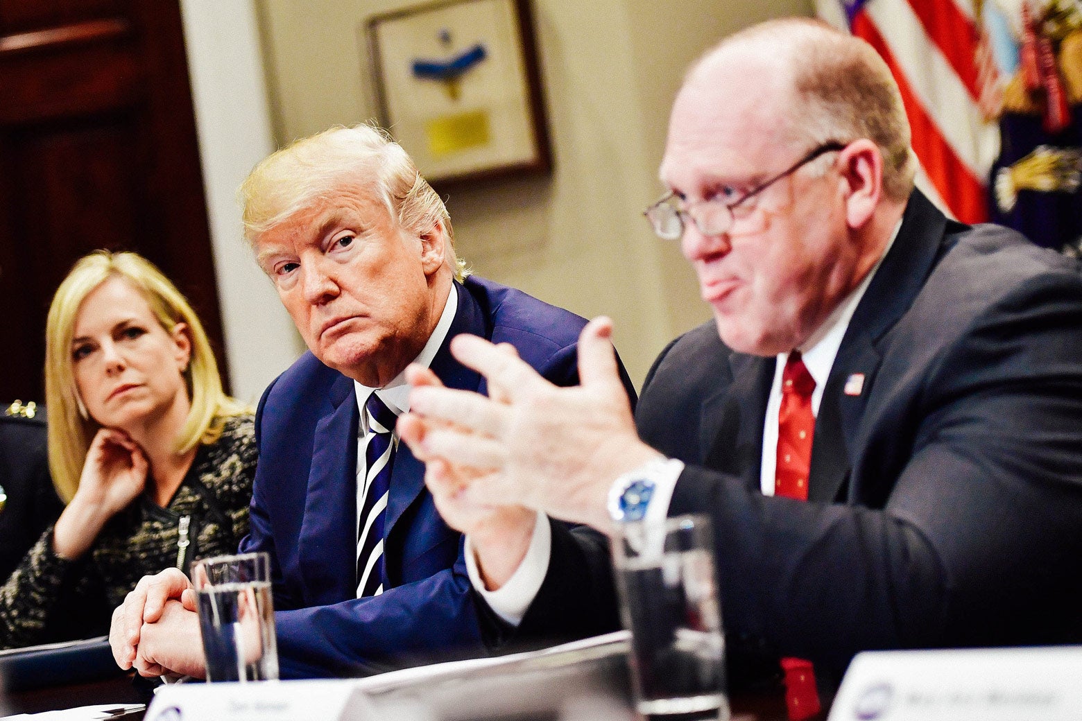 Kirstjen Nielsen, Donald Trump, and Thomas Homan at a conference table.