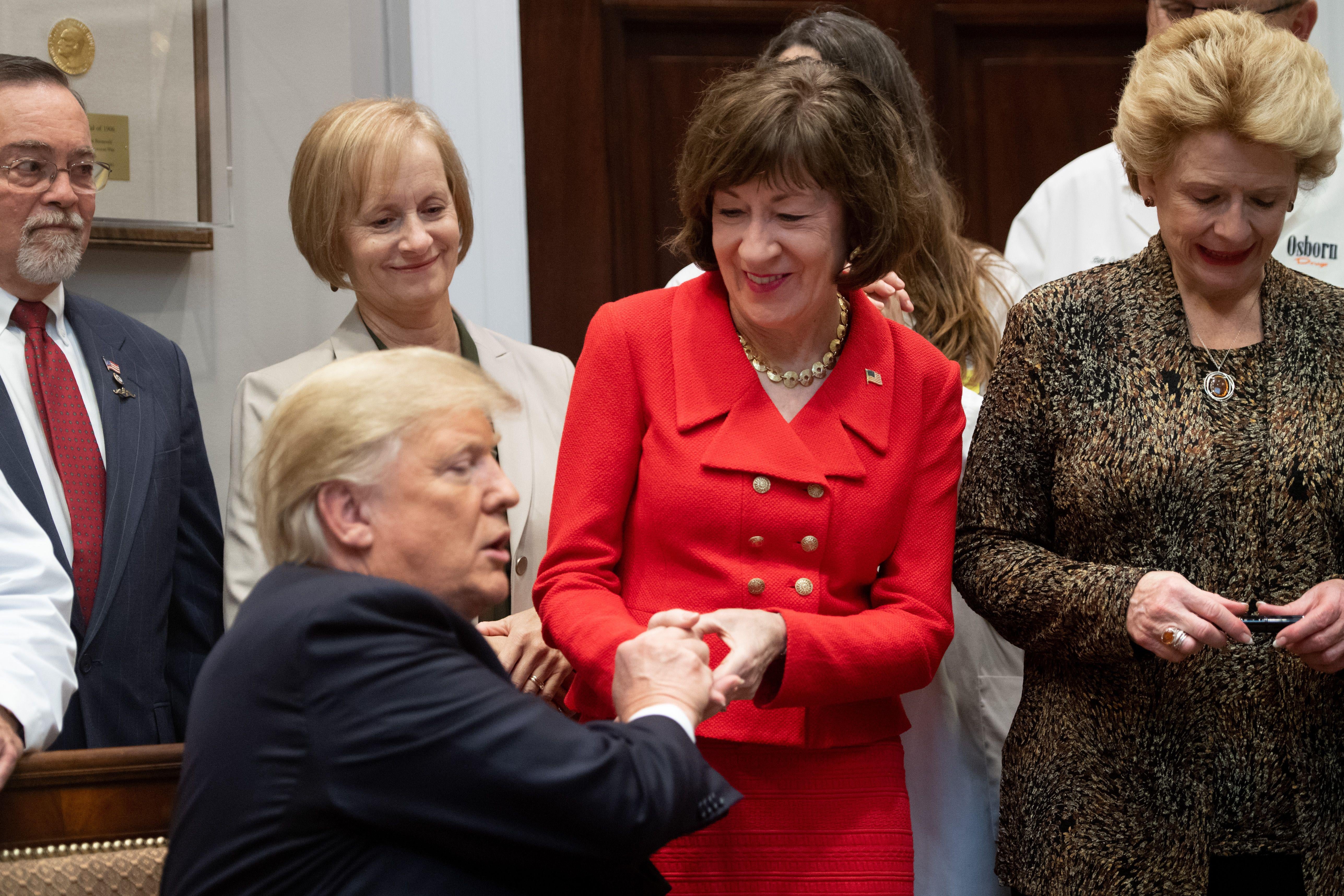 President Donald Trump presents Maine Sen. Susan Collins with a pen after signing bills intended to lower prescription drug prices during a ceremony on Oct. 10, 2018, in Washington.