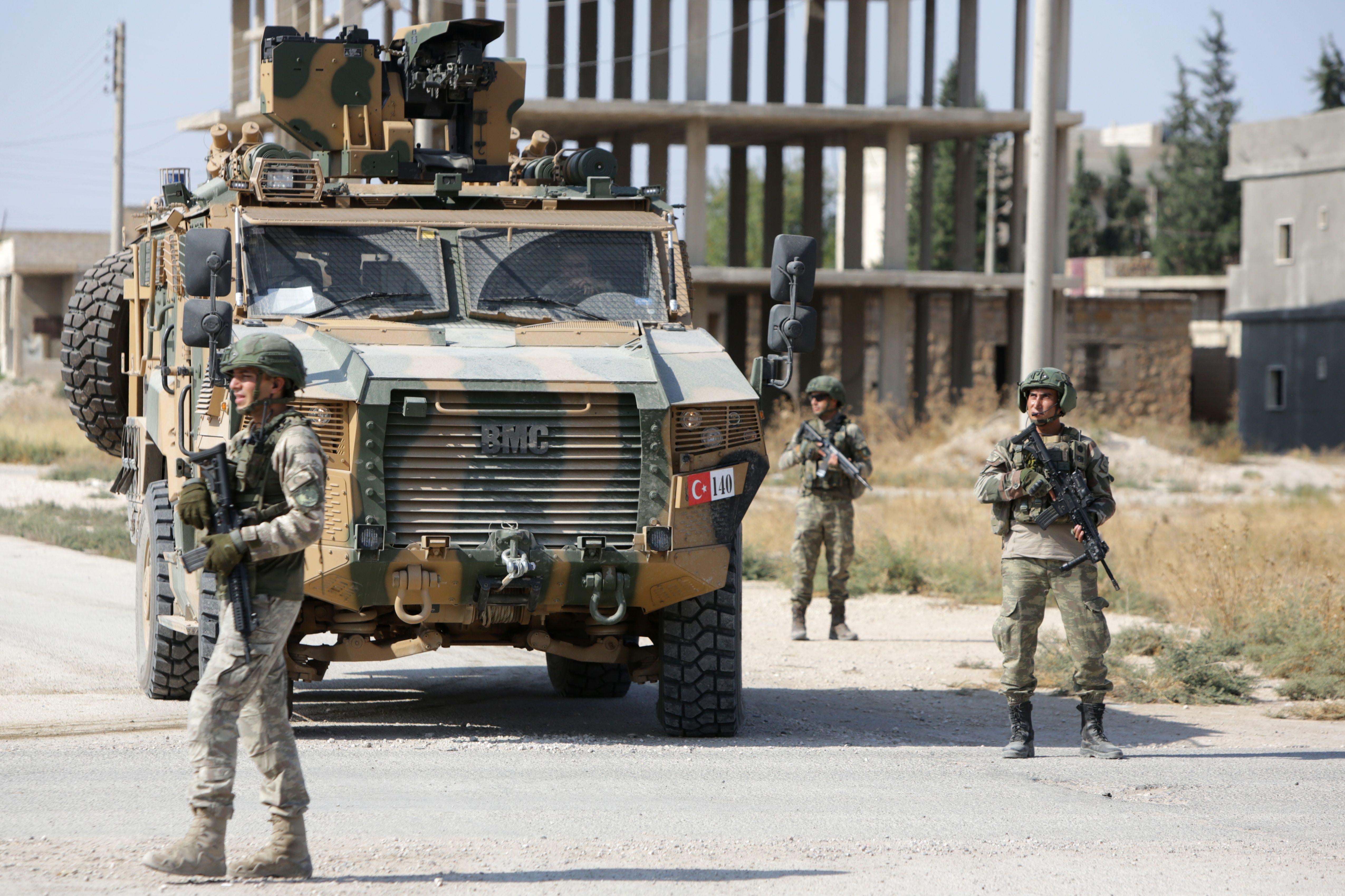 Turkish soldiers patrol a northern Syrian Kurdish town with tank.