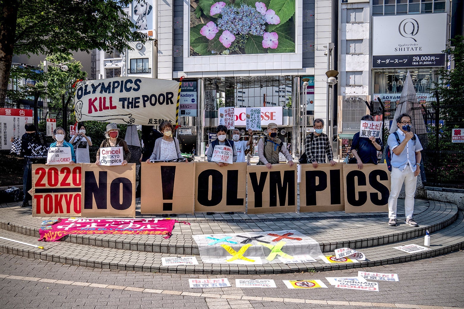 Protesters hold signs that spell out "No! Olympics."