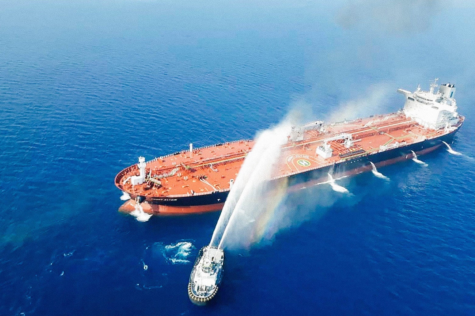 A tanker being hosed down from a navy boat.