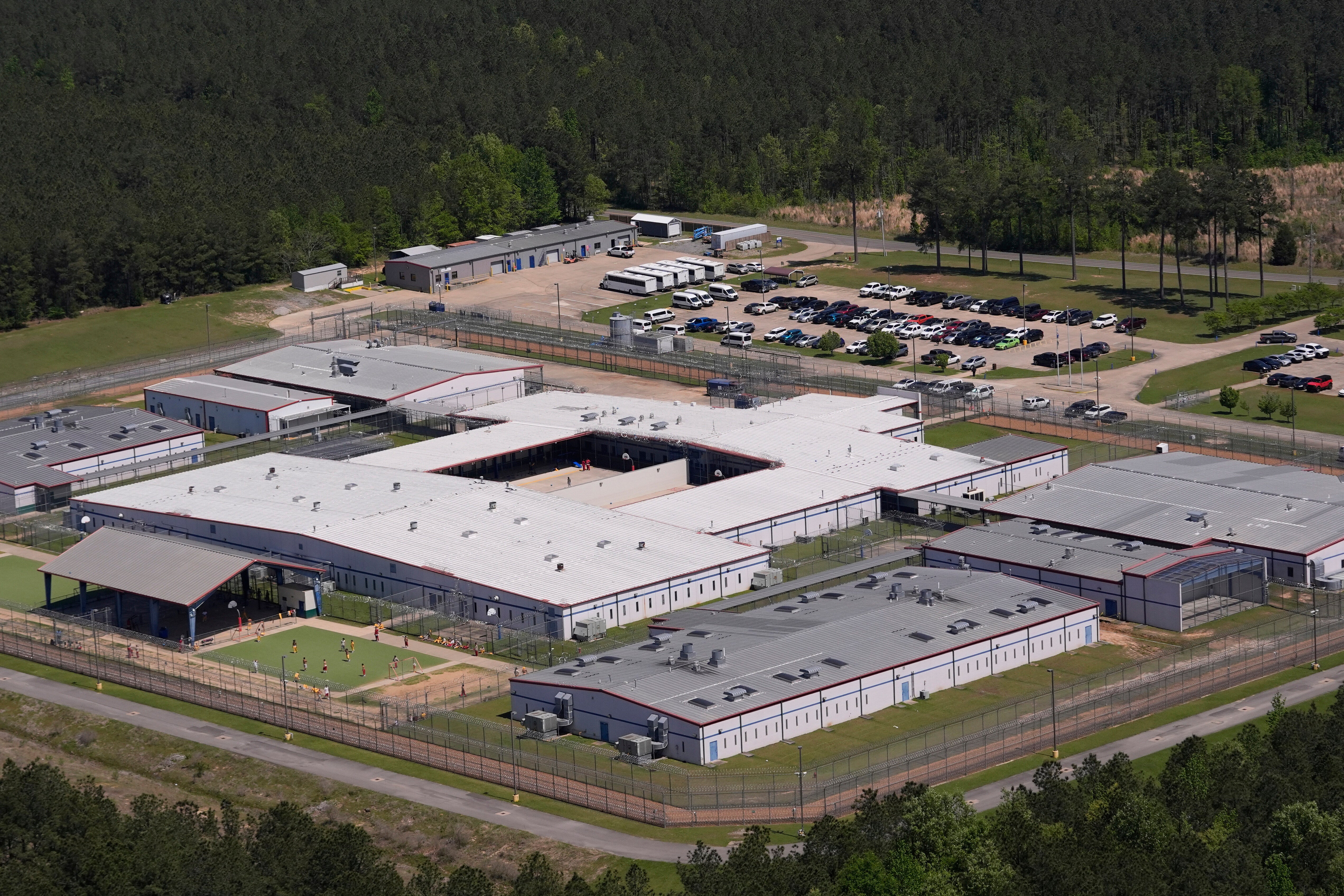 A sprawling prison complex seen overhead, surrounded by forest.