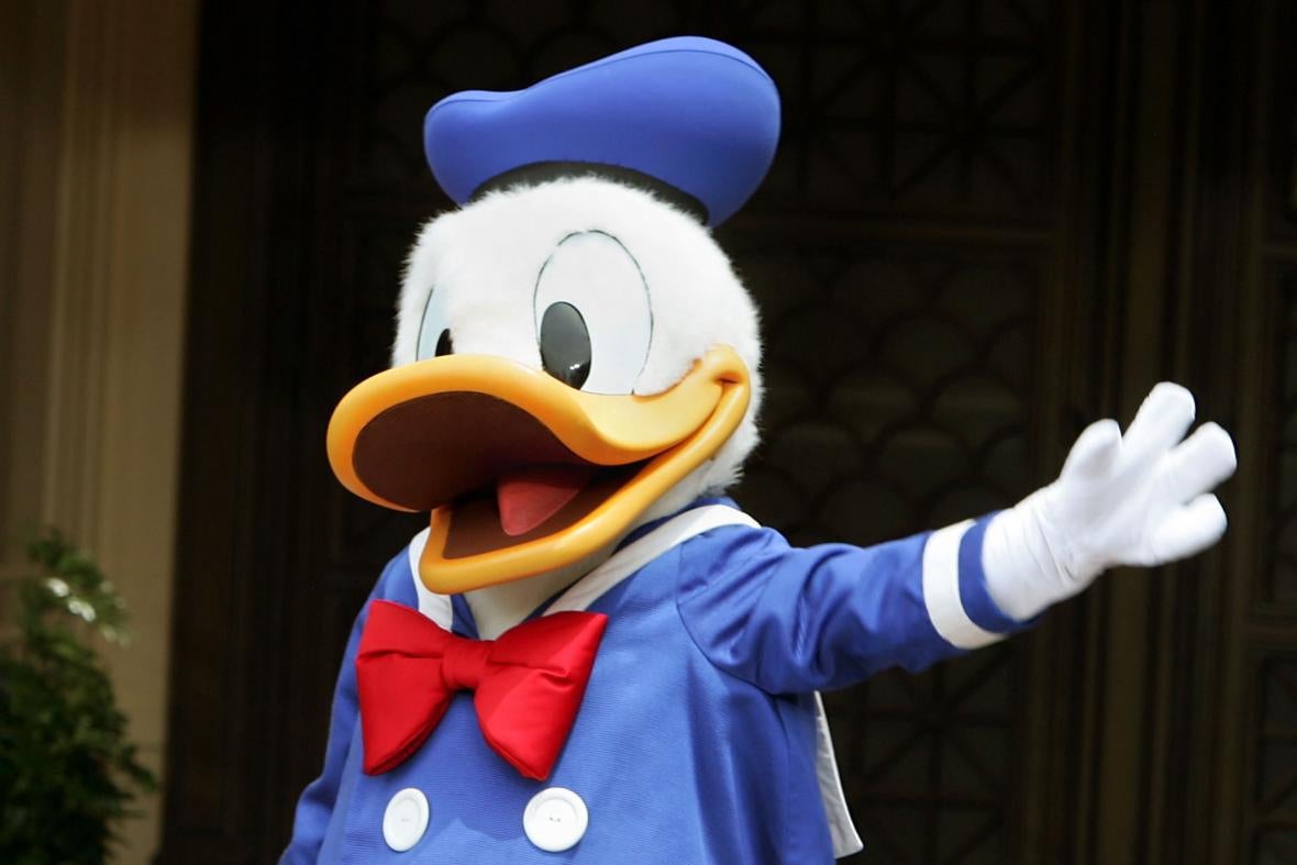 A person in a Donald Duck costume gestures with its hand.