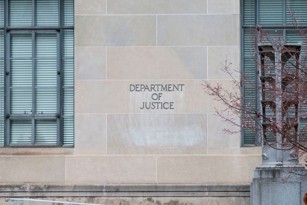 A brick wall between large windows with the words "Department of Justice" etched into it.