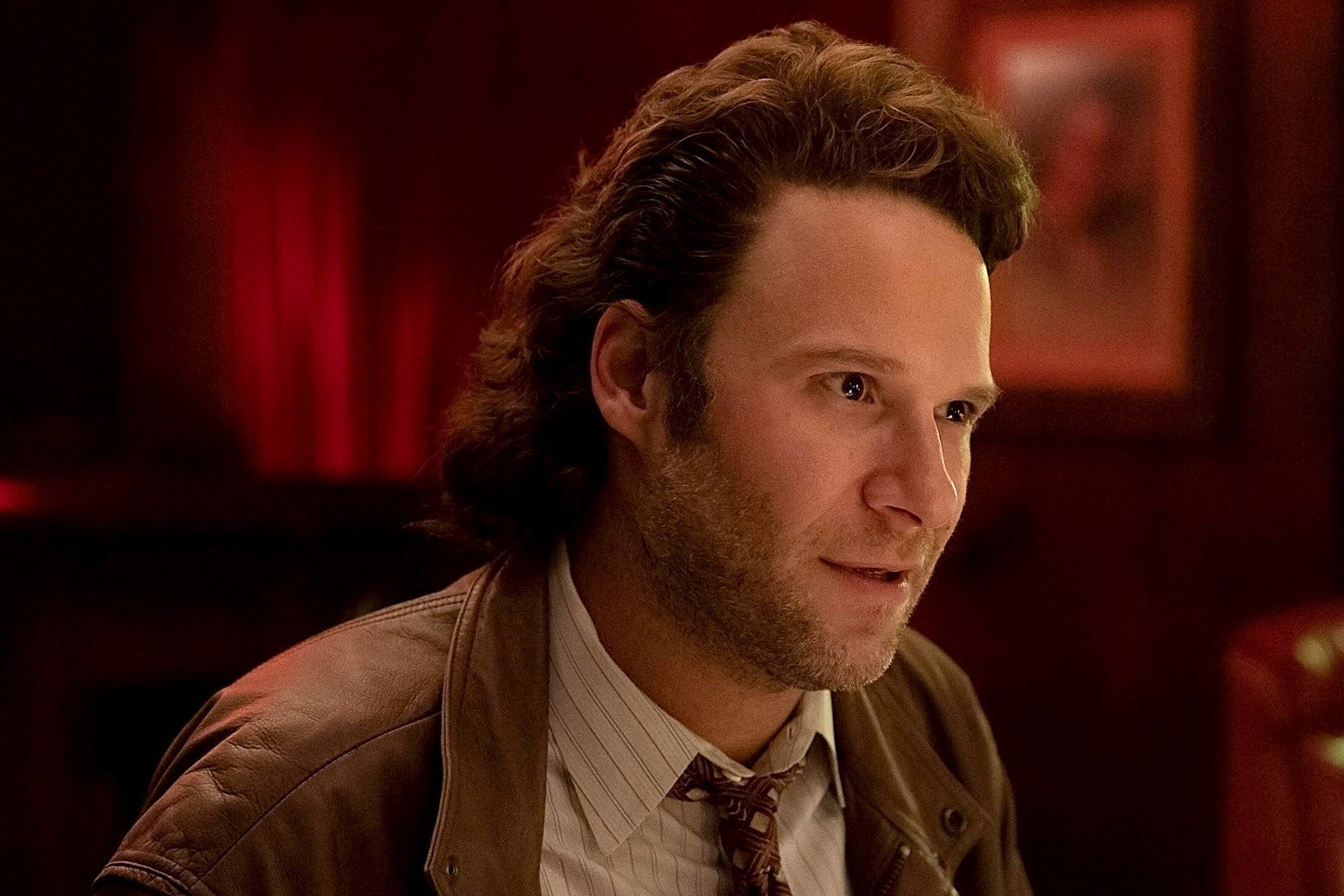 Rogen as Rand seated and leaning forward conspiratorially