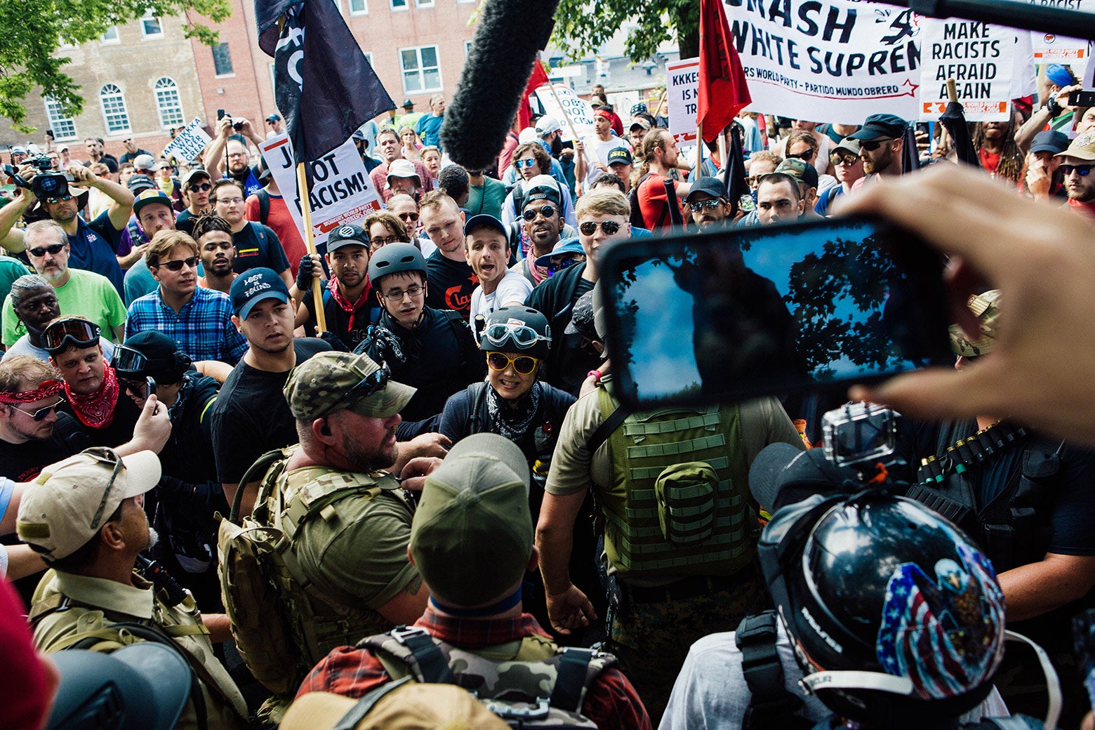 A diverse group of counterprotesters argues with protesters in military gear.