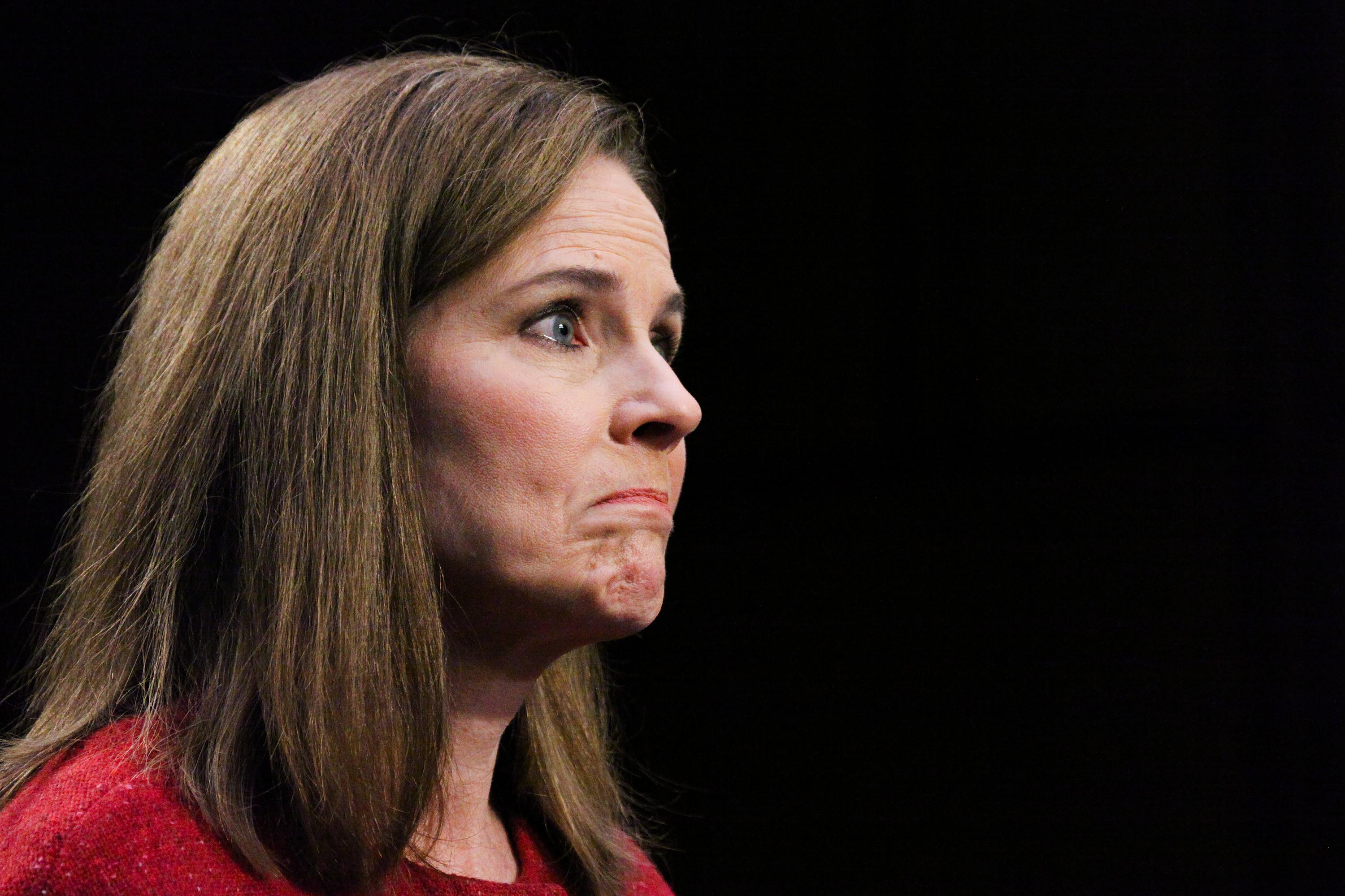 Supreme Court nominee Judge Amy Coney Barrett, from the side, frowning.