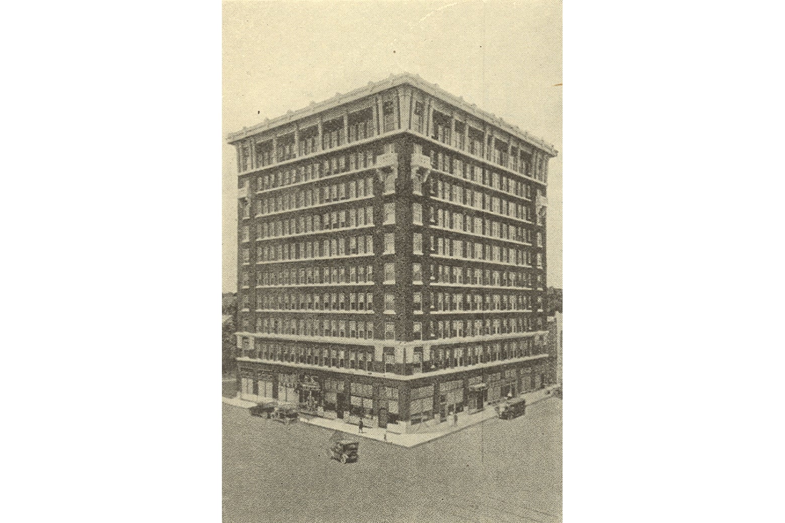 A ten-story brick building in 1916; automobiles are parked out front.