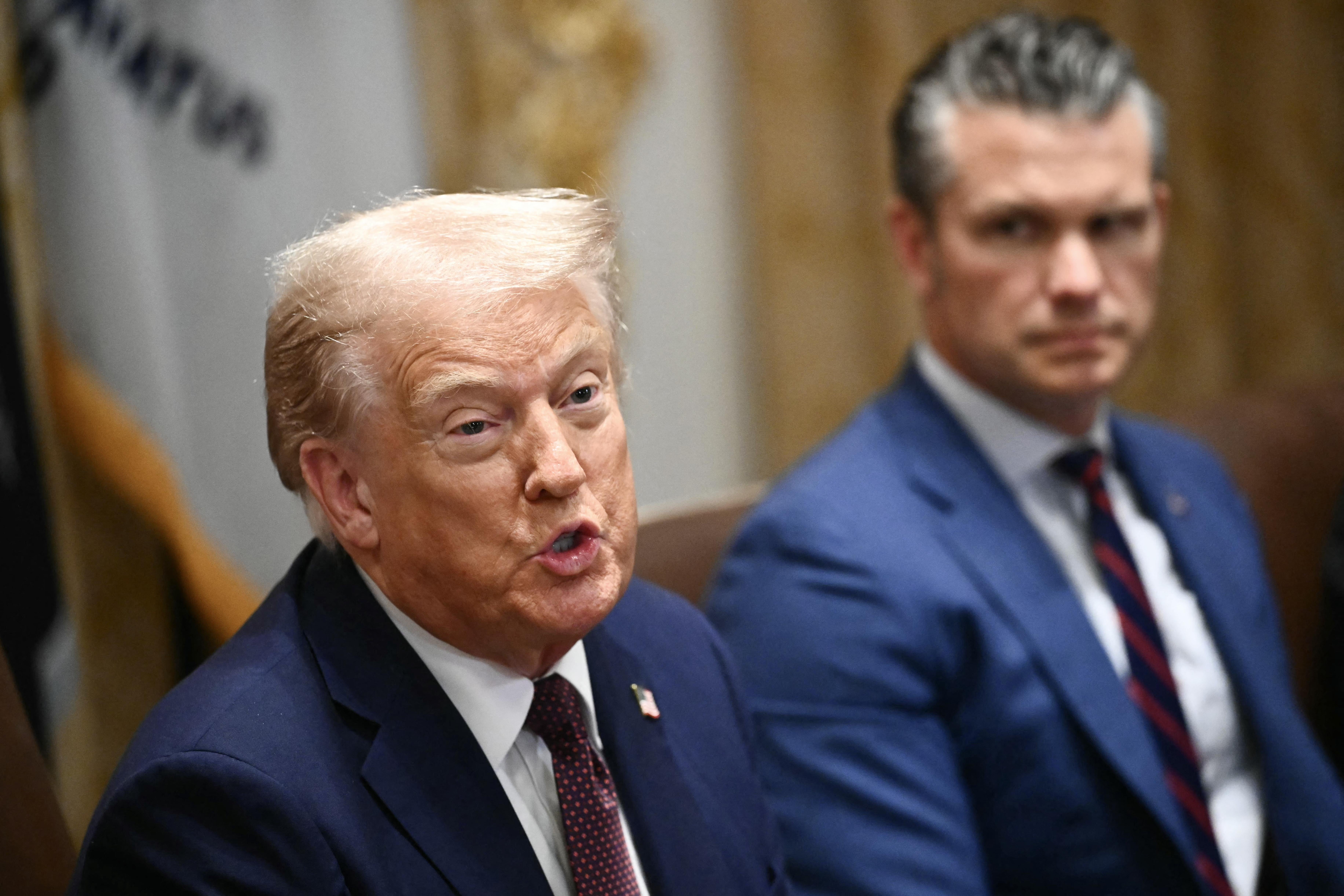Donald Trump e Pete Hegseth seduti a un tavolo da conferenza.