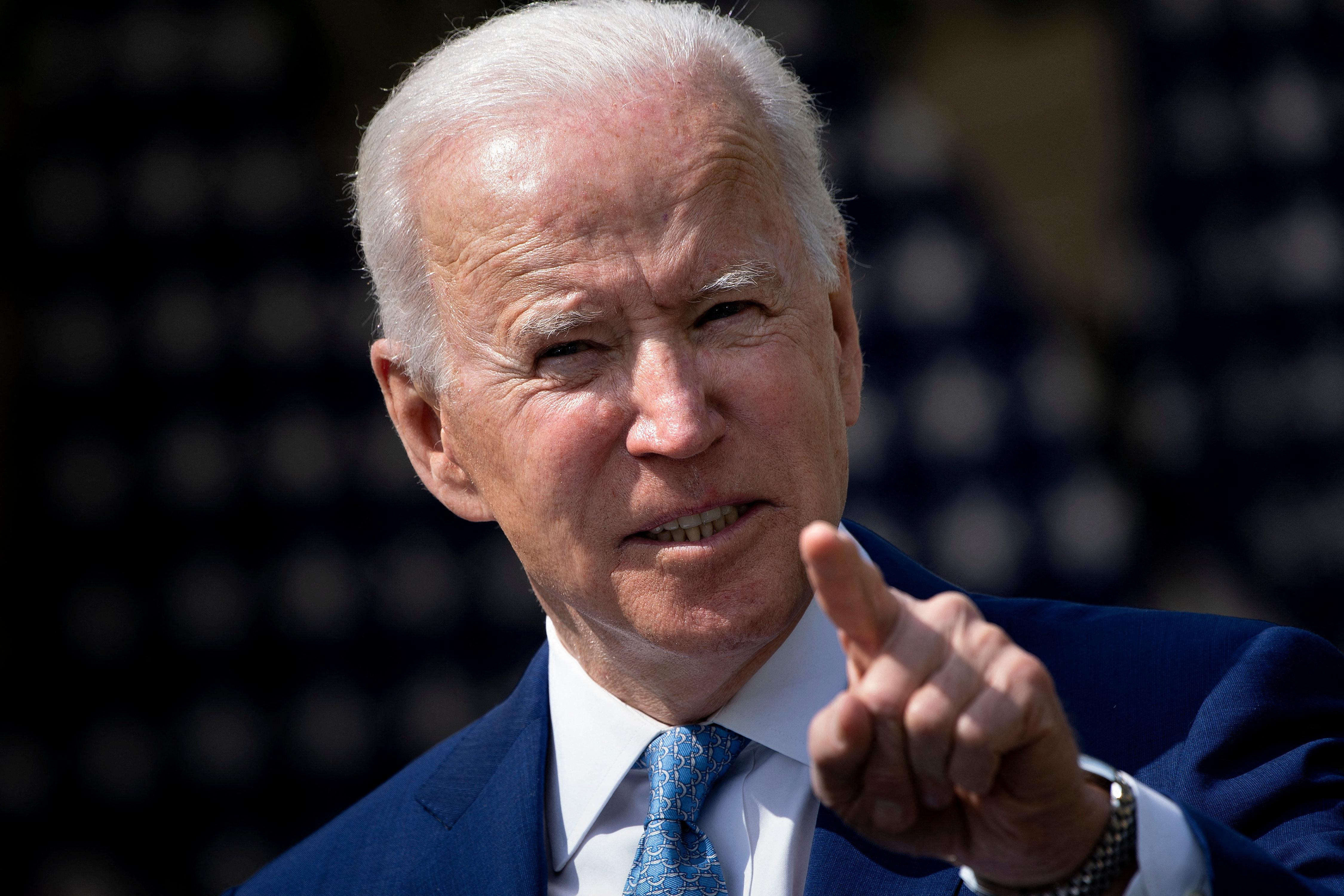 Joe Biden points while speaking from behind a podium in the Rose Garden of the White House.