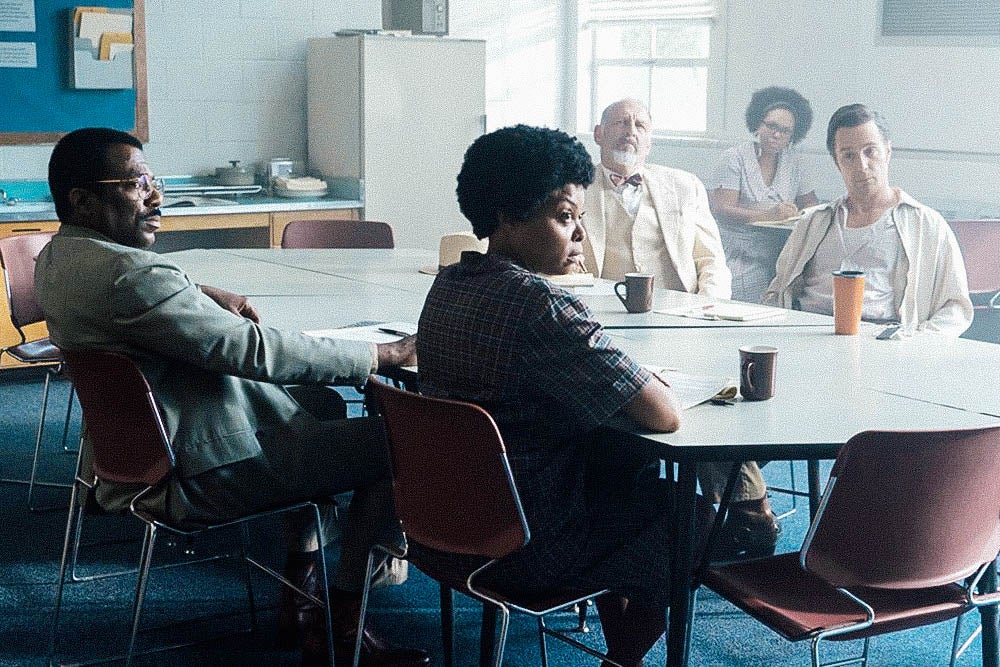 Taraji P. Henson and Sam Rockwell and other actors sit around a table in a still from The Best of Enemies.