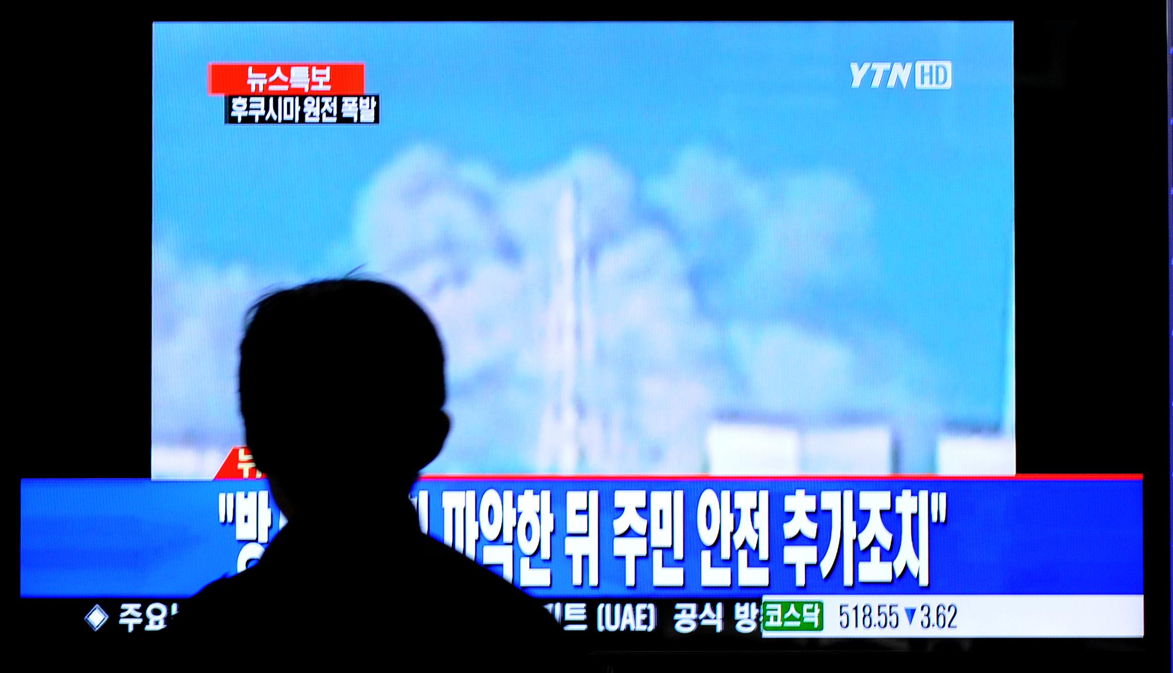 A South Korean passenger watches TV showing Japan's Fukushima No. 1 atomic plant spewing fumes.
