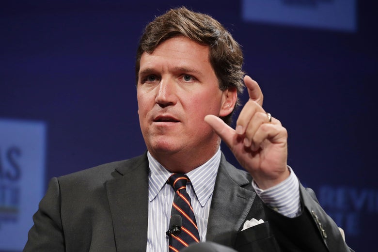 Tucker Carlson talks and holds up his fingers.