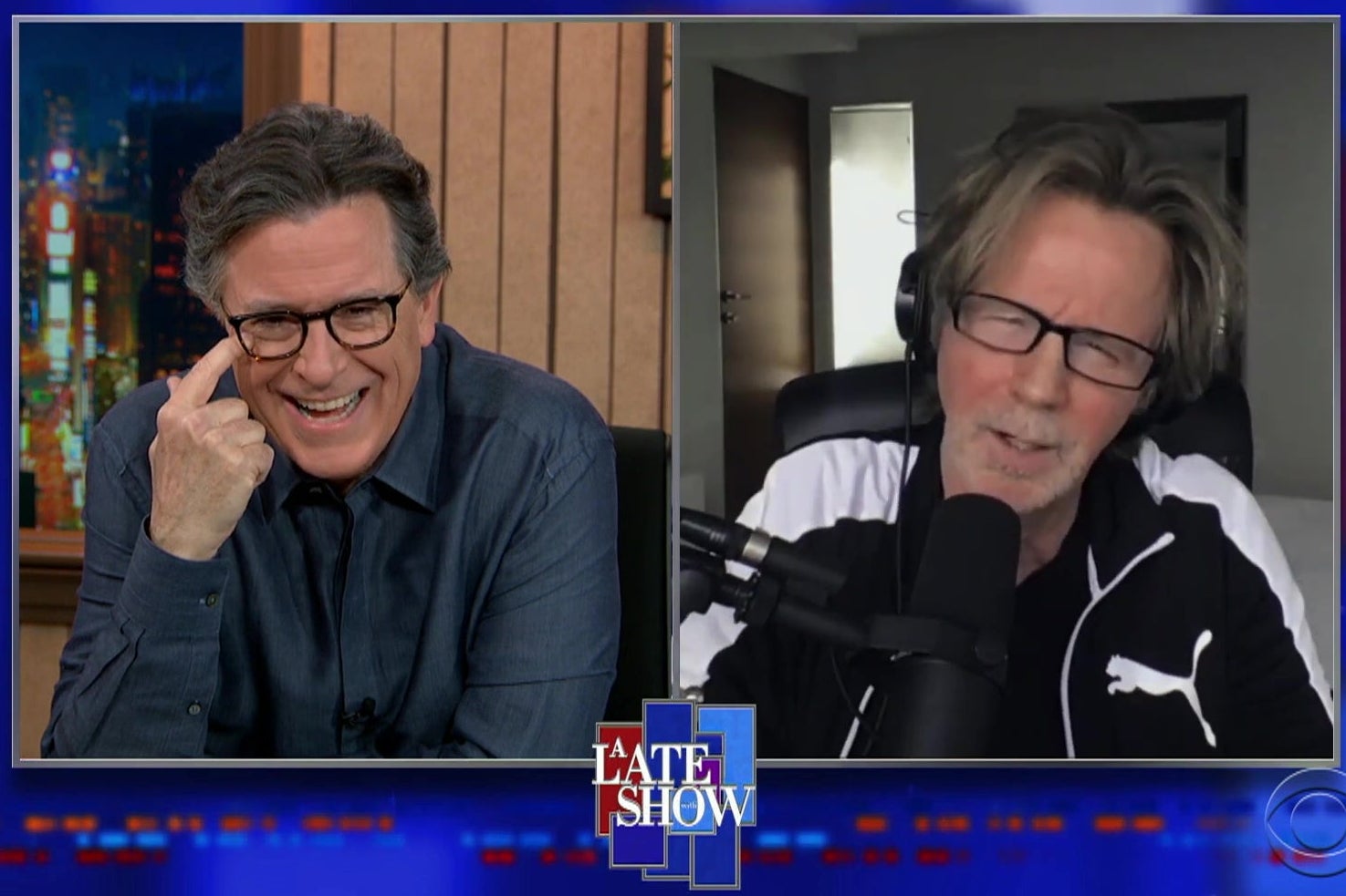 A split screen showing Stephen COlbert in one view, laughing, and Dana Carvey, in a black and white Puma track suit, impersonating Joe Biden.