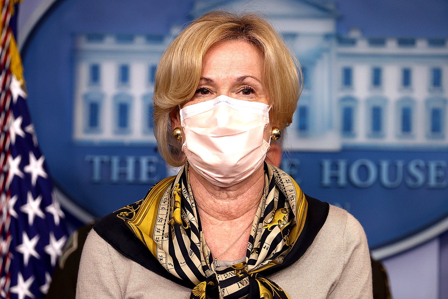Birx wearing a mask and a scarf, standing in front of the White House logo in the press briefing room