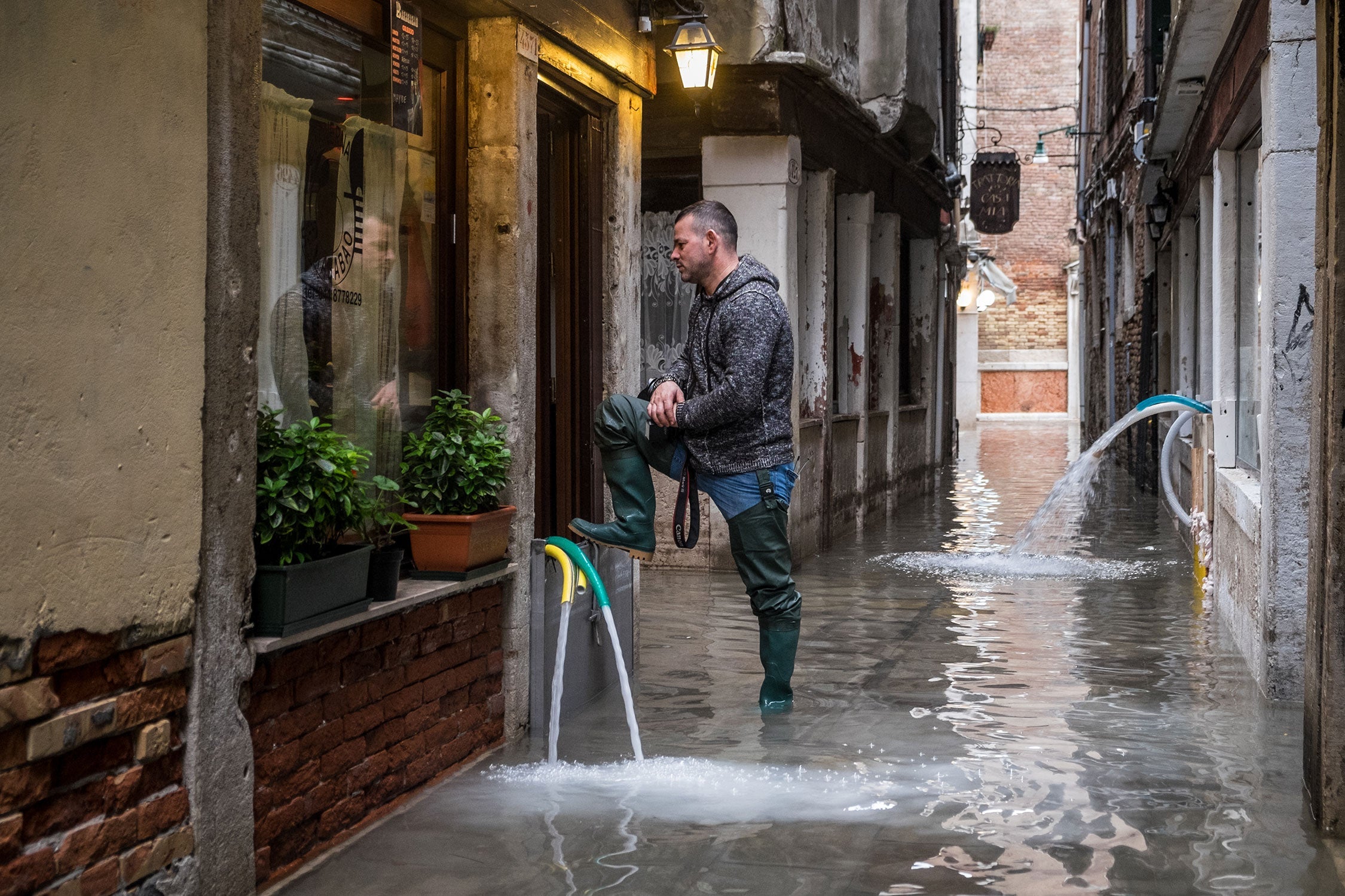 A man staring at his restaurant damaged by flooding, in Venice.