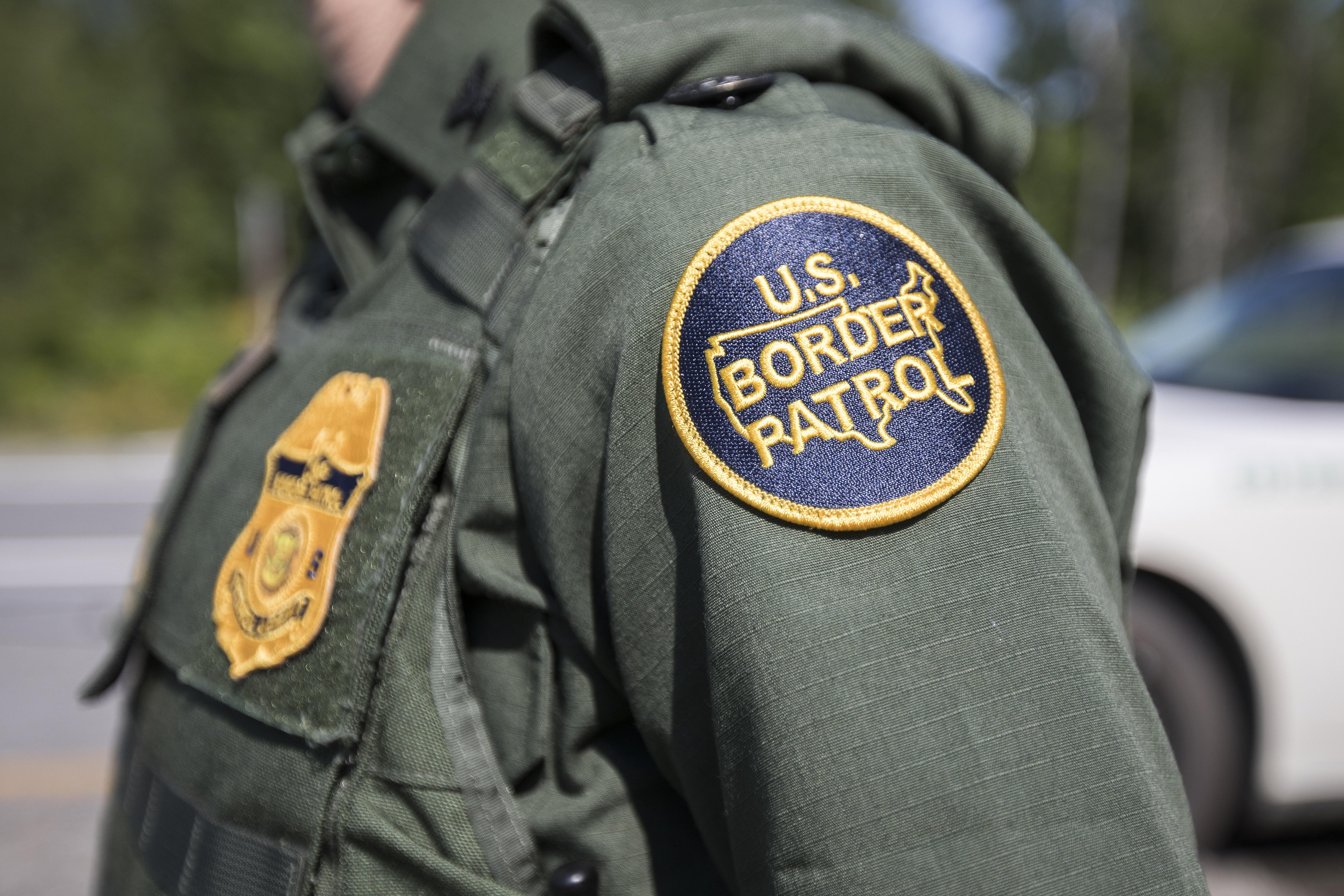 The shoulder of a Border Patrol agent is seen, with the institution's patch prominently displayed.