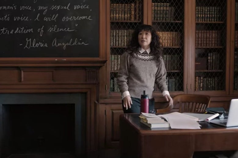 Dr. Kim stands at the front of a grand-looking college classroom with bookshelves and a blackboard behind her.