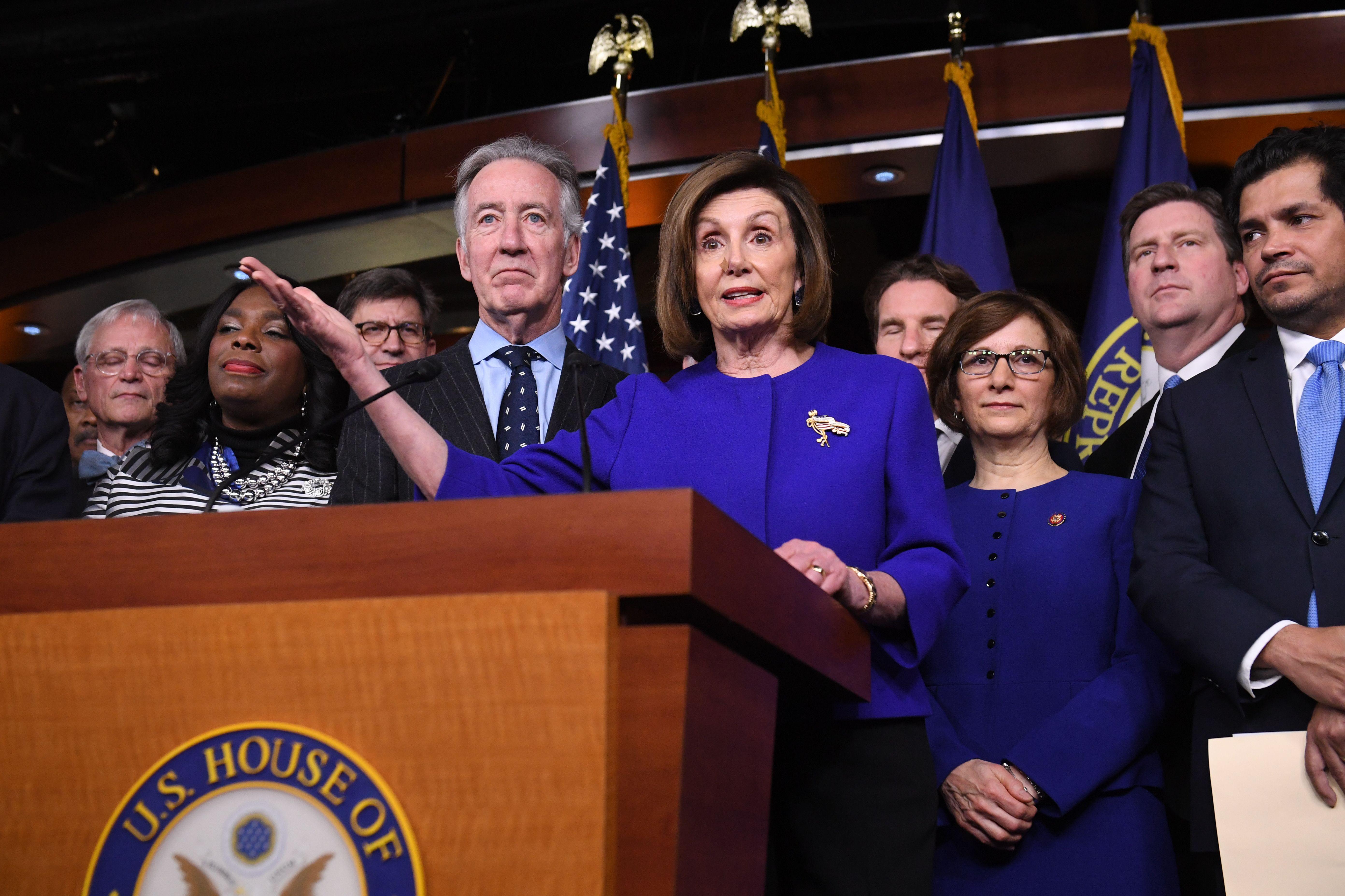 Nancy Pelosi, surrounded by other congressional leaders, speaks at a lectern.