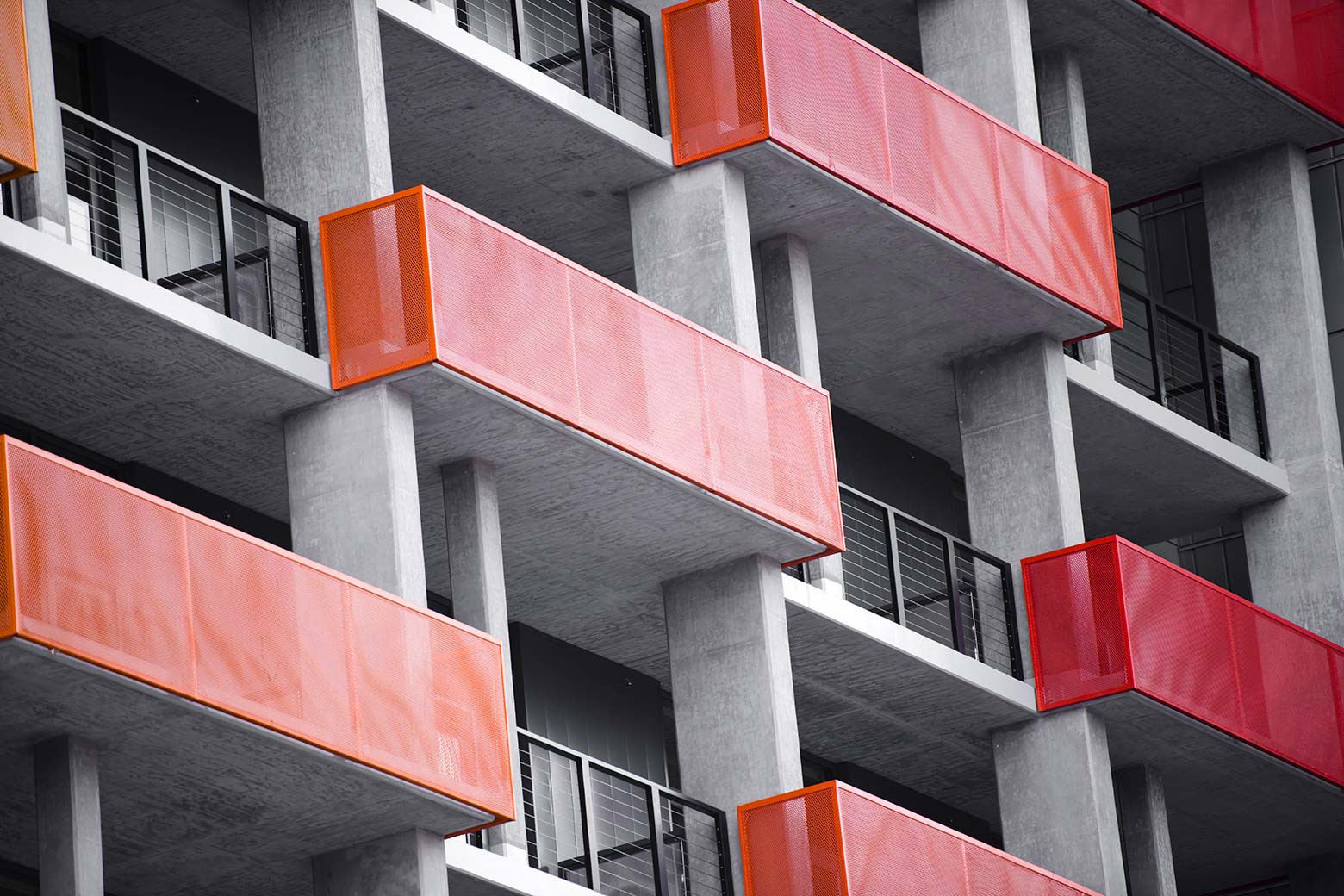 Orange and red balconies on a modern concrete high-rise building.