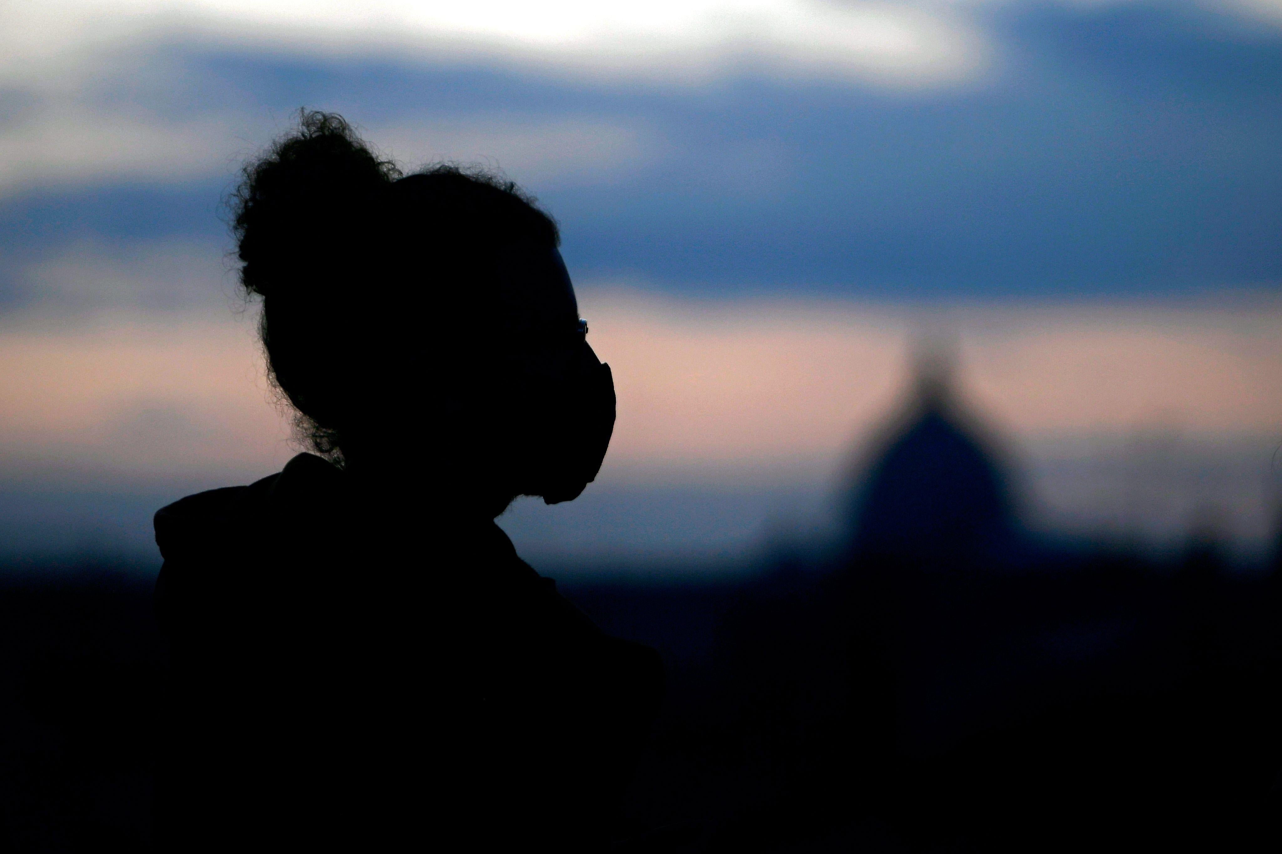 A person in a face mask at dusk